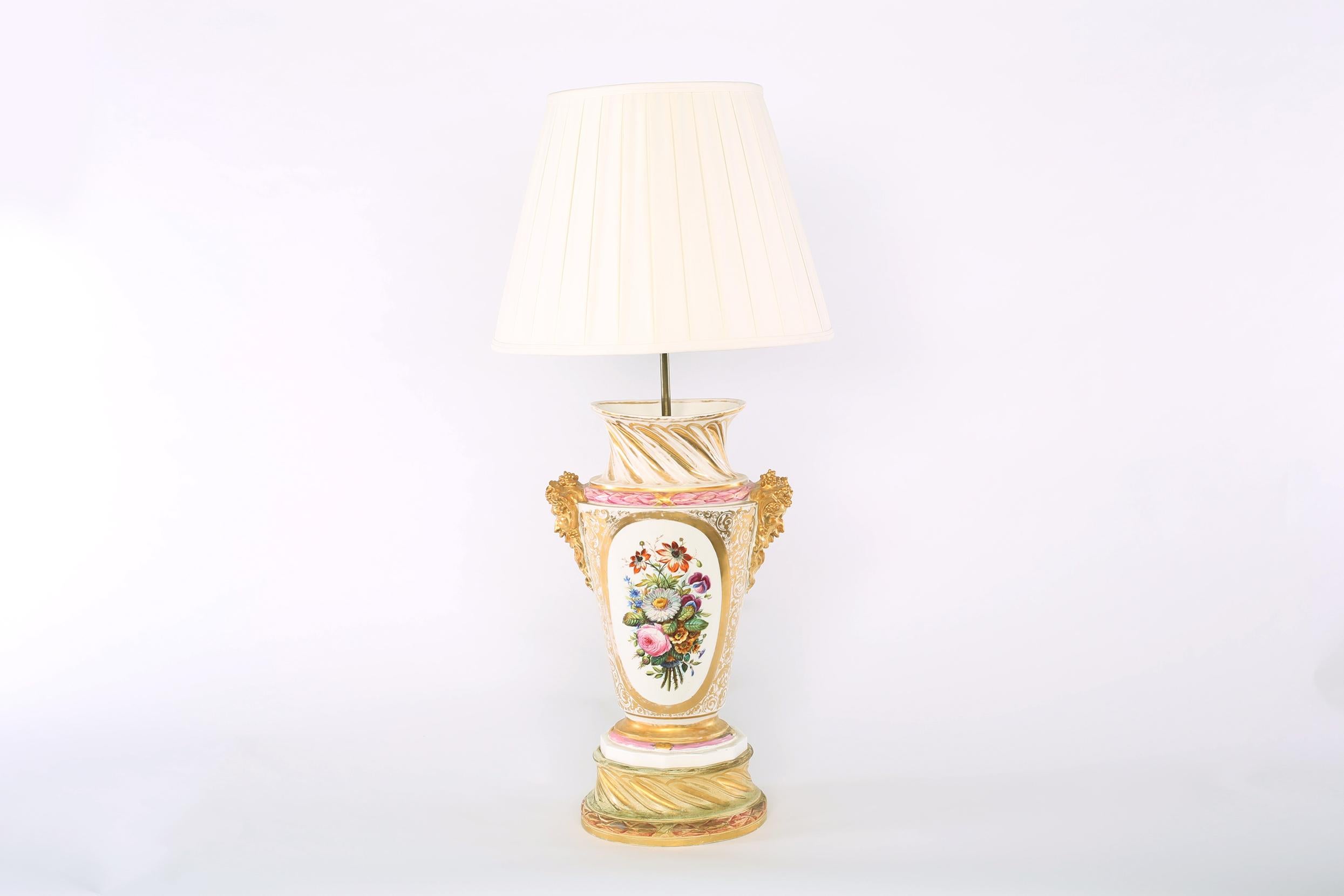 Large pair gilt Porcelain urn shape with exterior floral design details table / task lamps. Each lamp is in good working condition. Minor wear appropriate with age / use. Each lamp stand about 38.5 inches high x 18 inches wide. Each one comes with a