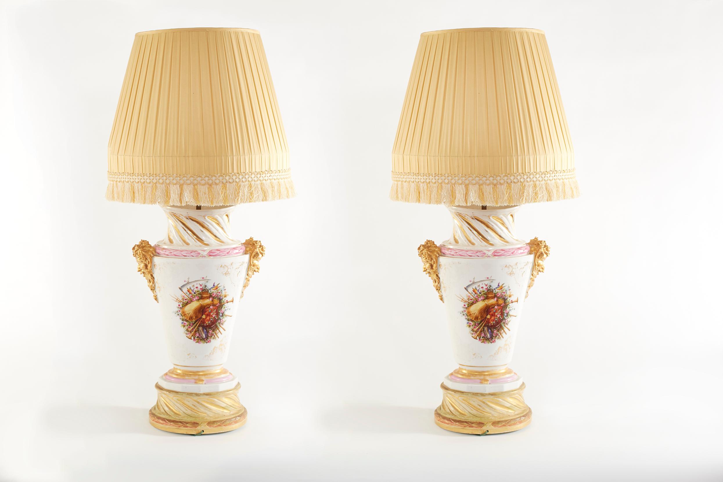 Large pair gilt porcelain urn shape with exterior floral design details table / task lamps. Each lamp is in good working condition. Minor wear appropriate with age / use. Each lamp stand about 38.5 inches high x 18 inches wide. Each one comes with a