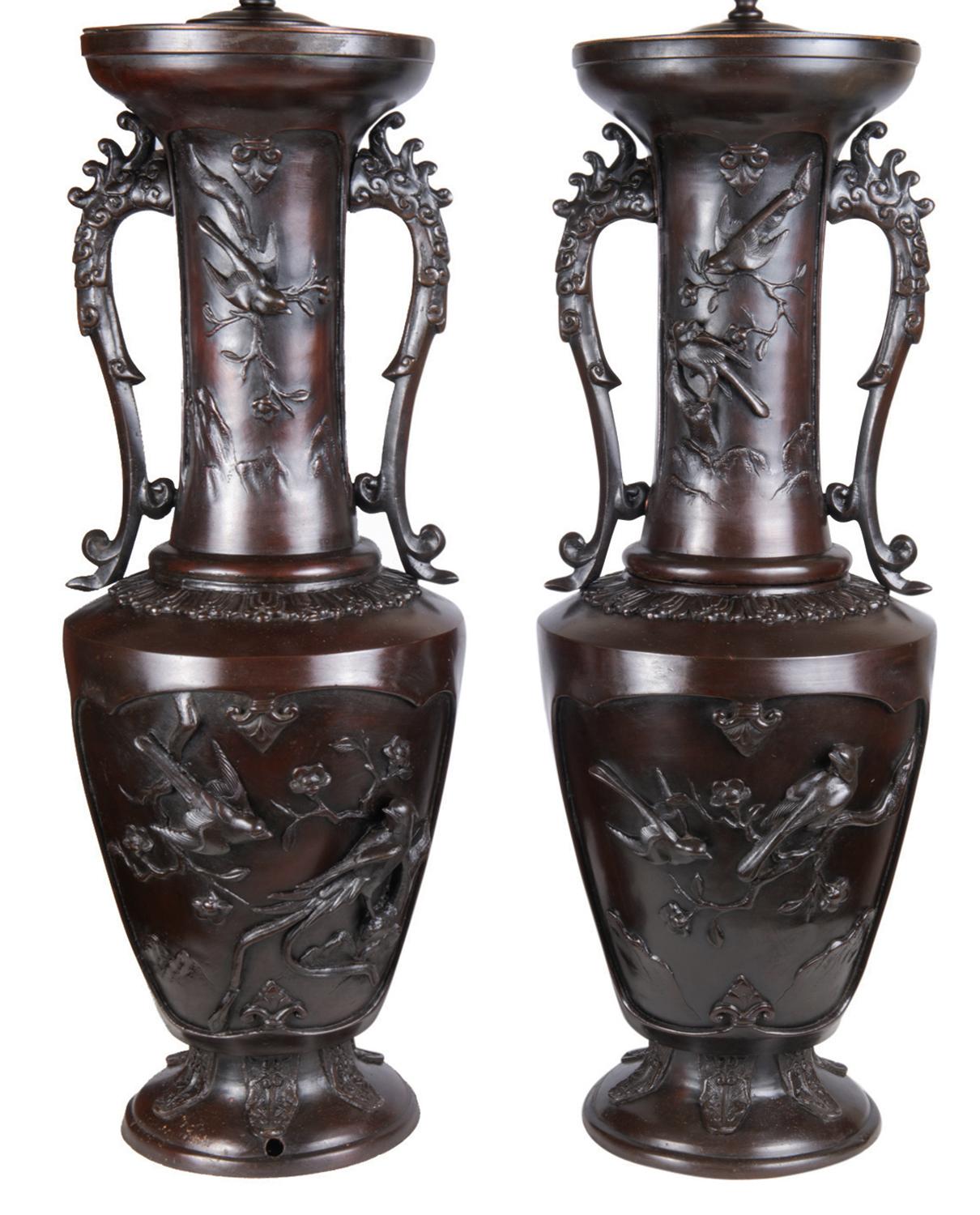 Une paire très impressionnante et frappante de vases / lampes en bronze patiné et gaufré du 19ème siècle (période Meiji 1868-1912). Chacune d'elles comporte des panneaux d'oiseaux et de plantes exotiques, ainsi que des poignées ressemblant à des
