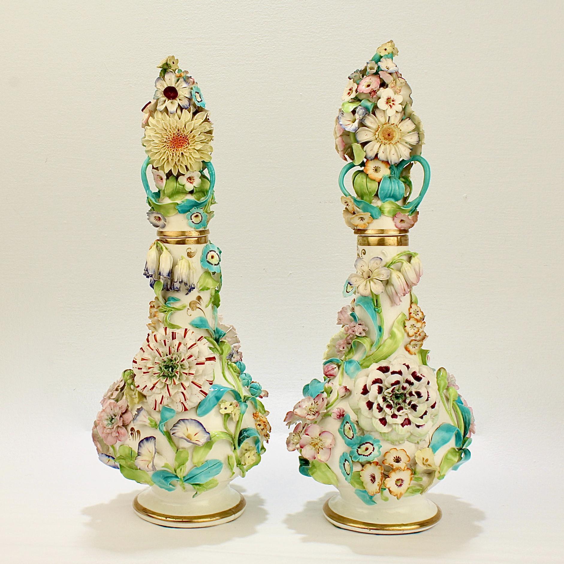 A wonderful pair of very large, early 19th century English porcelain decanters or bottles. 

They are either perfume bottles or lidded vases and have elaborate, full figural flower encrusted decoration throughout. 

The floral encrustation is