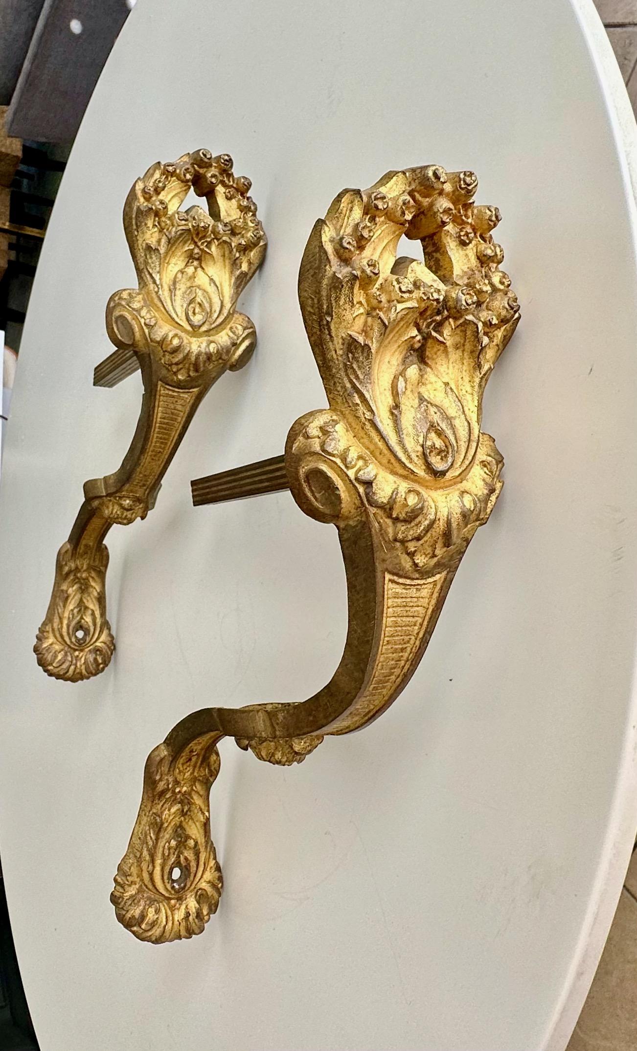 An antique French Louis XVI-style pair of gilt bronze curtain hooks or tie-backs richly decorated with acanthus leaf and floral motif.