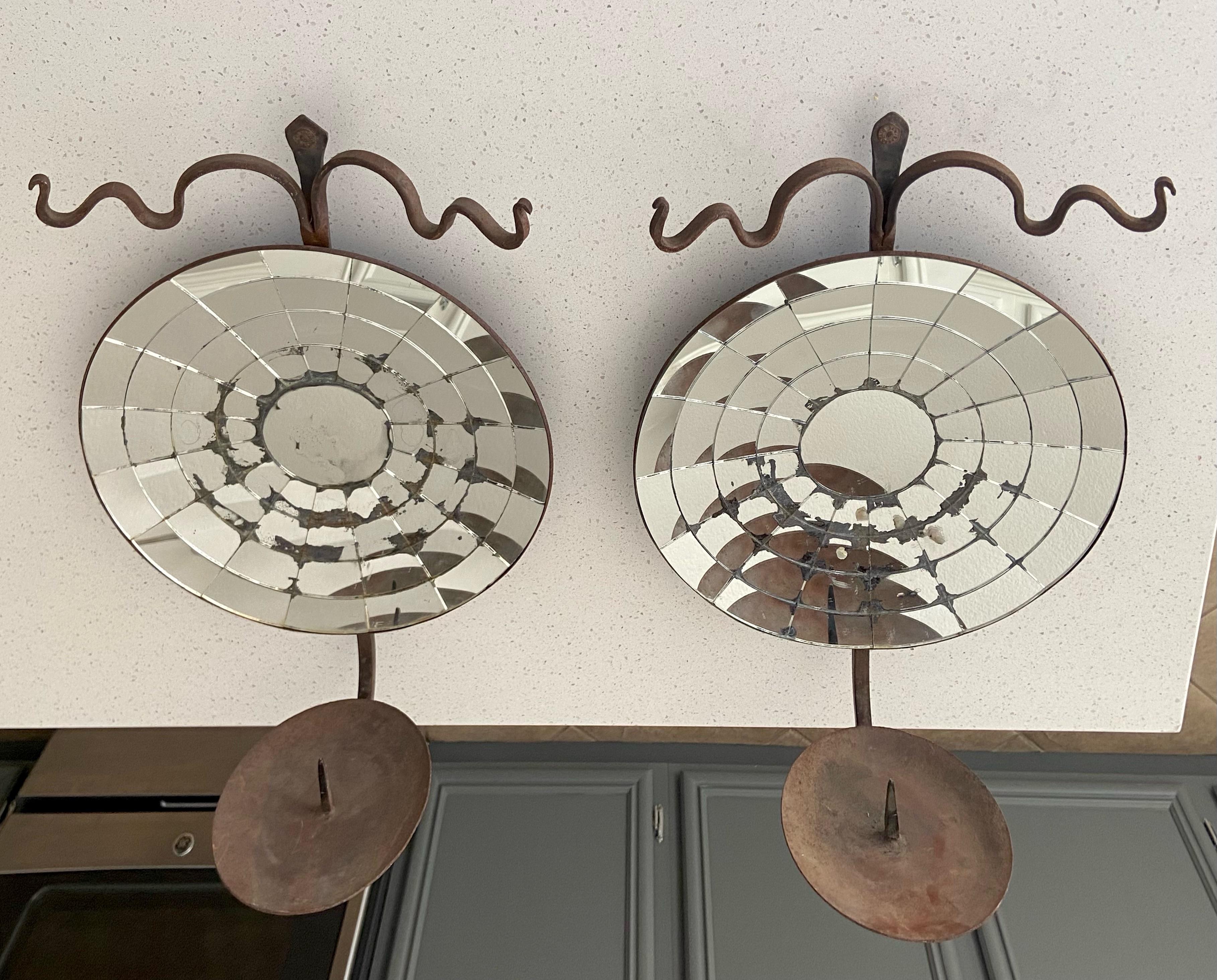 Pair large Colonial American style concave mirrored reflector candle sconces with iron body and arm. The sconces are made in the later 20th century but made to look antique with oxidation and patina to spider web mirror and iron frame. Made by well