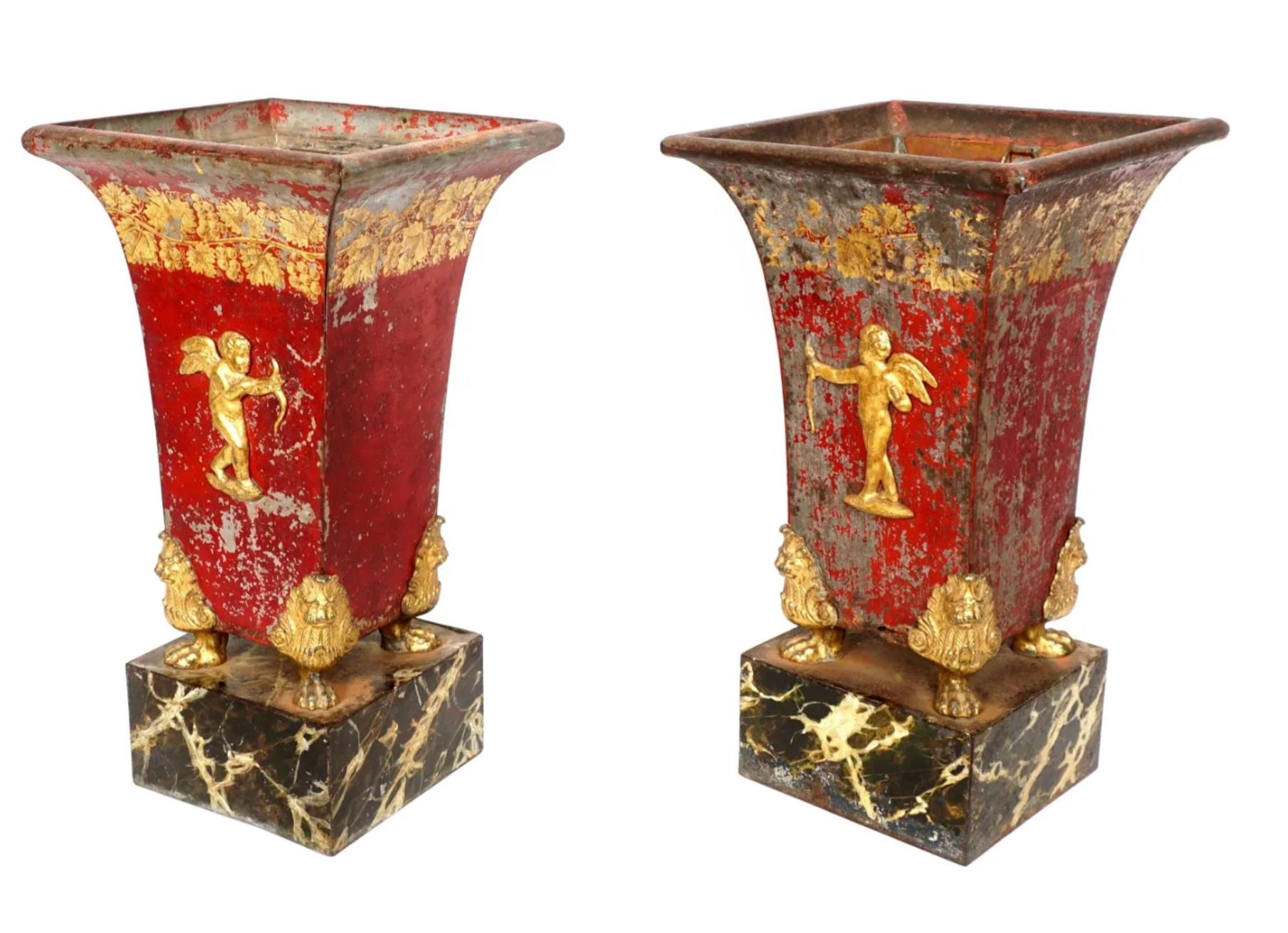Spectacular large pair of French Empire Tole painted metal cache pot vases with applied gilt bronze cupid, on four gilt bronze paw feet. Lower faux marble painted metal bases. Both with copper inserts. Original painted finish time worn to a