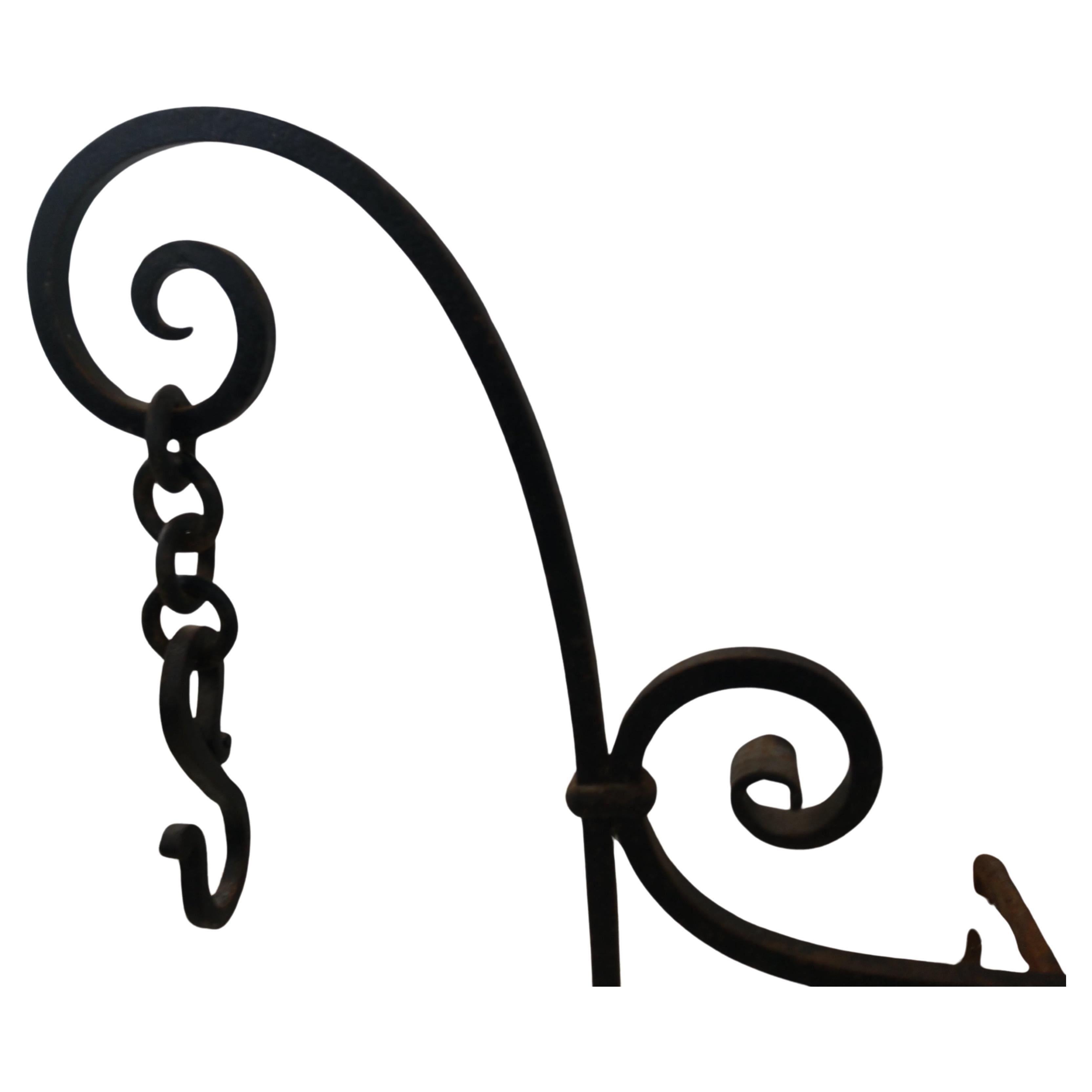 Favolosa coppia di androni forgiati a mano in stile coloniale spagnolo. Set completo di tre con la barra di collegamento per la stabilità. Con il braccio oscillante per scaldare le pentole e il portabottiglie nella parte superiore, questi oggetti