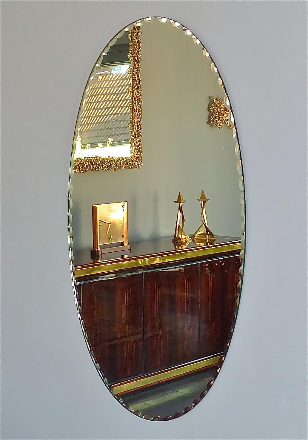 Rare large pair of Italian Midcentury oval mirrors with faceted crystal glass and attribution to Fontana Arte or Cristal Arte, Italy around 1950s. The reverse with cardboard and patinated brass hangers for vertical or horizontal installation. The