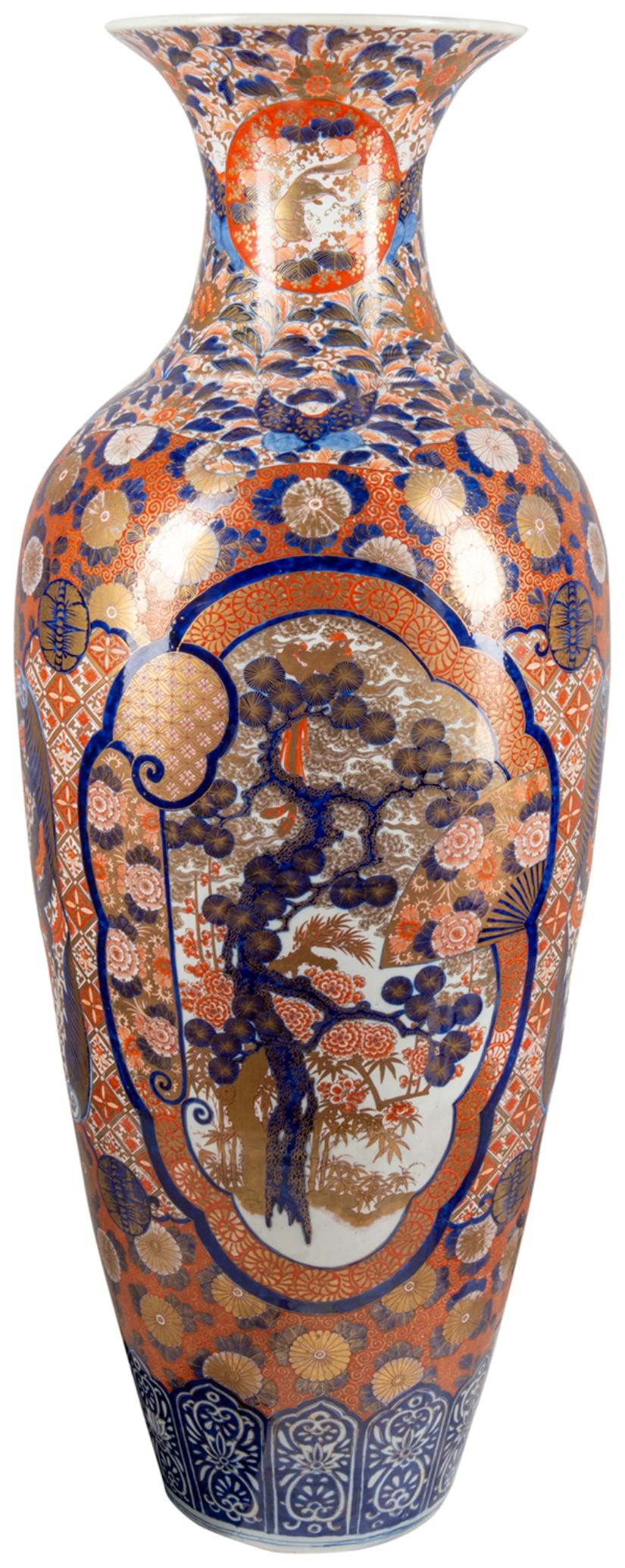 A large very good quality pair of Meiji period (1868-1912) Japanese Imari porcelain vases, each with the classical red and blue ground, with classical flower, leaf and motif decoration, inset hand painted panels depicting blossom trees, fans and