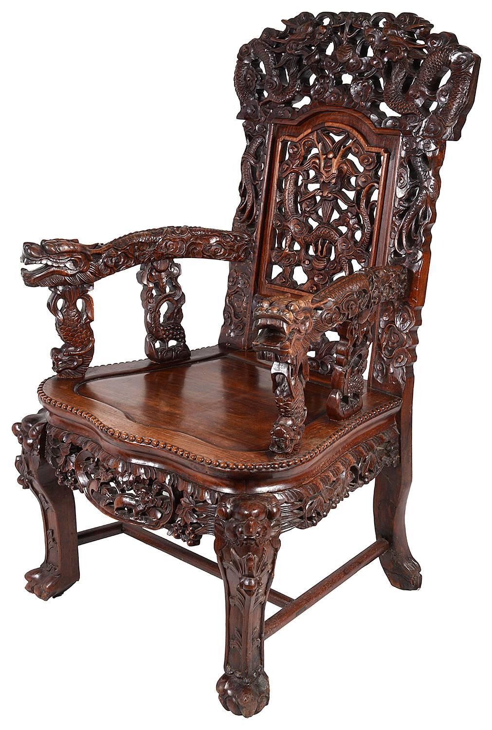 A very impressive and good quality pair of Chinese hardwood armchairs. Having carved mythical dragons and clouds all-over, an inset panelled seat, raised on carved legs terminating in claw feet.