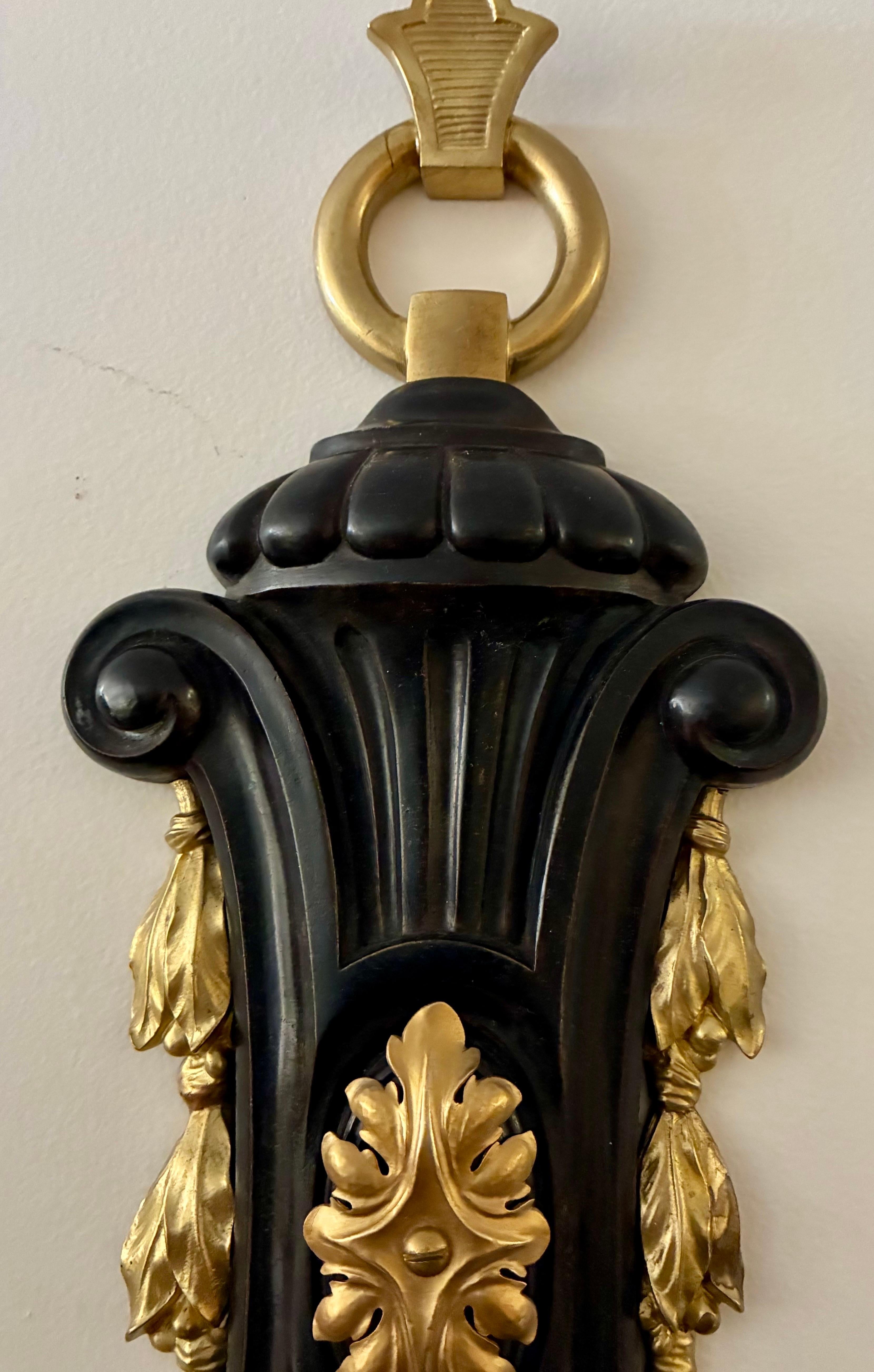 This large and impressive pair of bronze sconces are well cast and finely detailed. The patinated backs are accented with gilt bronze decorative mounts that feature Classical motifs.
The sconces are newly wired and ready for use.