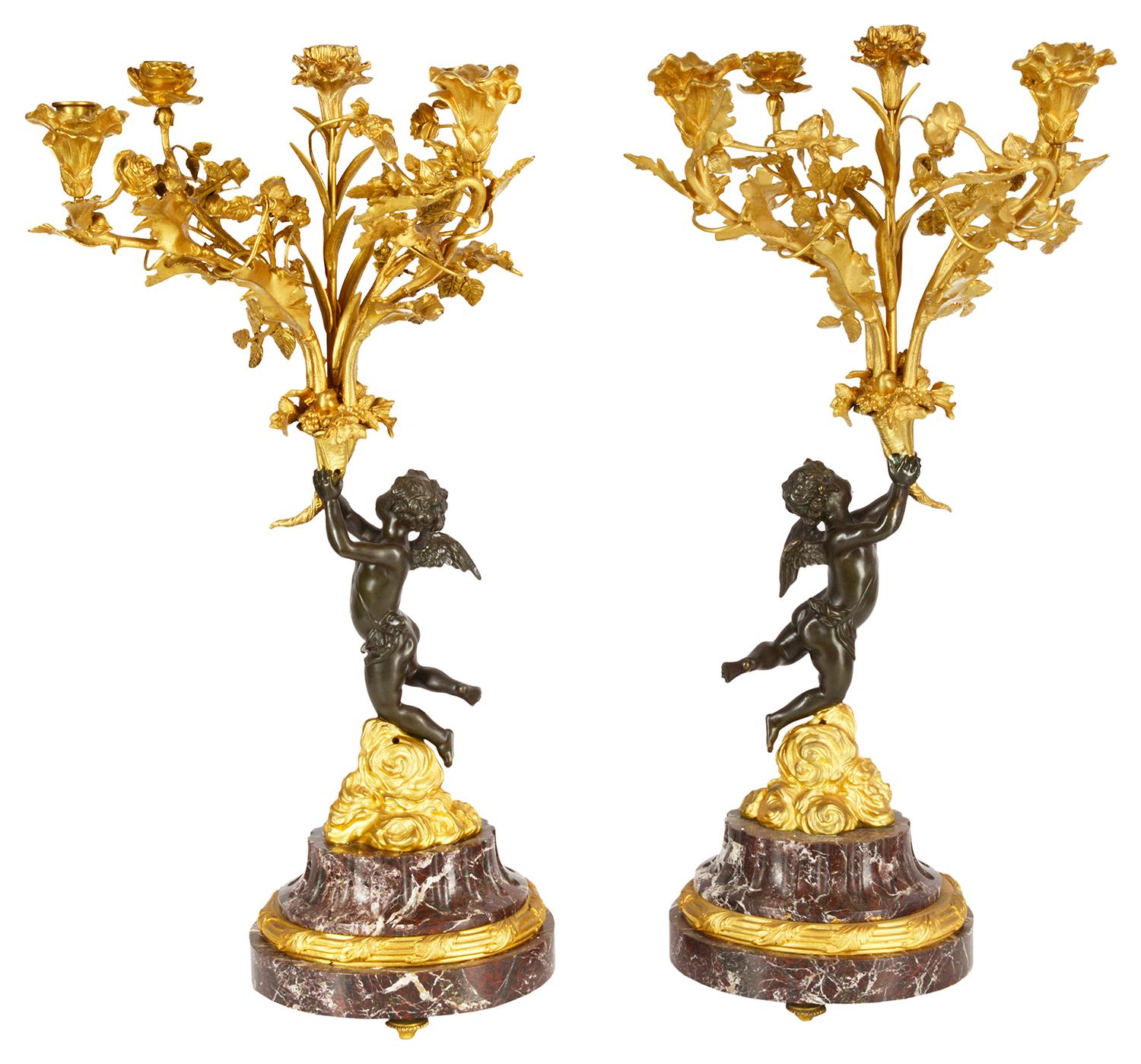 A good quality large pair of French Louis XVI style candelabra. Each having 5 branch gilded ormolu sconces with flowers and leaf decoration, supported by a pair of bronze patinated winged cherubs on clouds and mounted on rouge marble fluted bases.