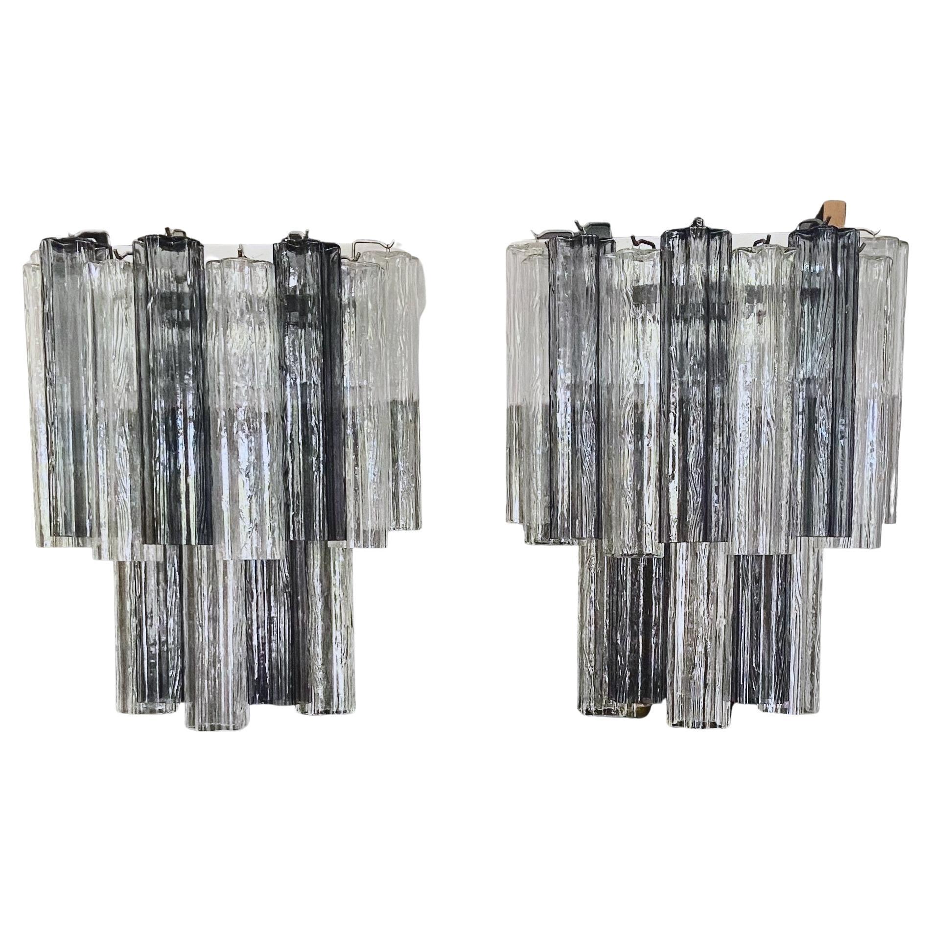 Zwei große italienische Tronchi-Wandleuchter aus Glas mit verchromter Rückwand. Die Farbe der Murano-Glasröhren ist eine Kombination aus klar und rauchgrau. Jede Leuchte ist mit 6 Kandelaber-Glühbirnen bestückt. 