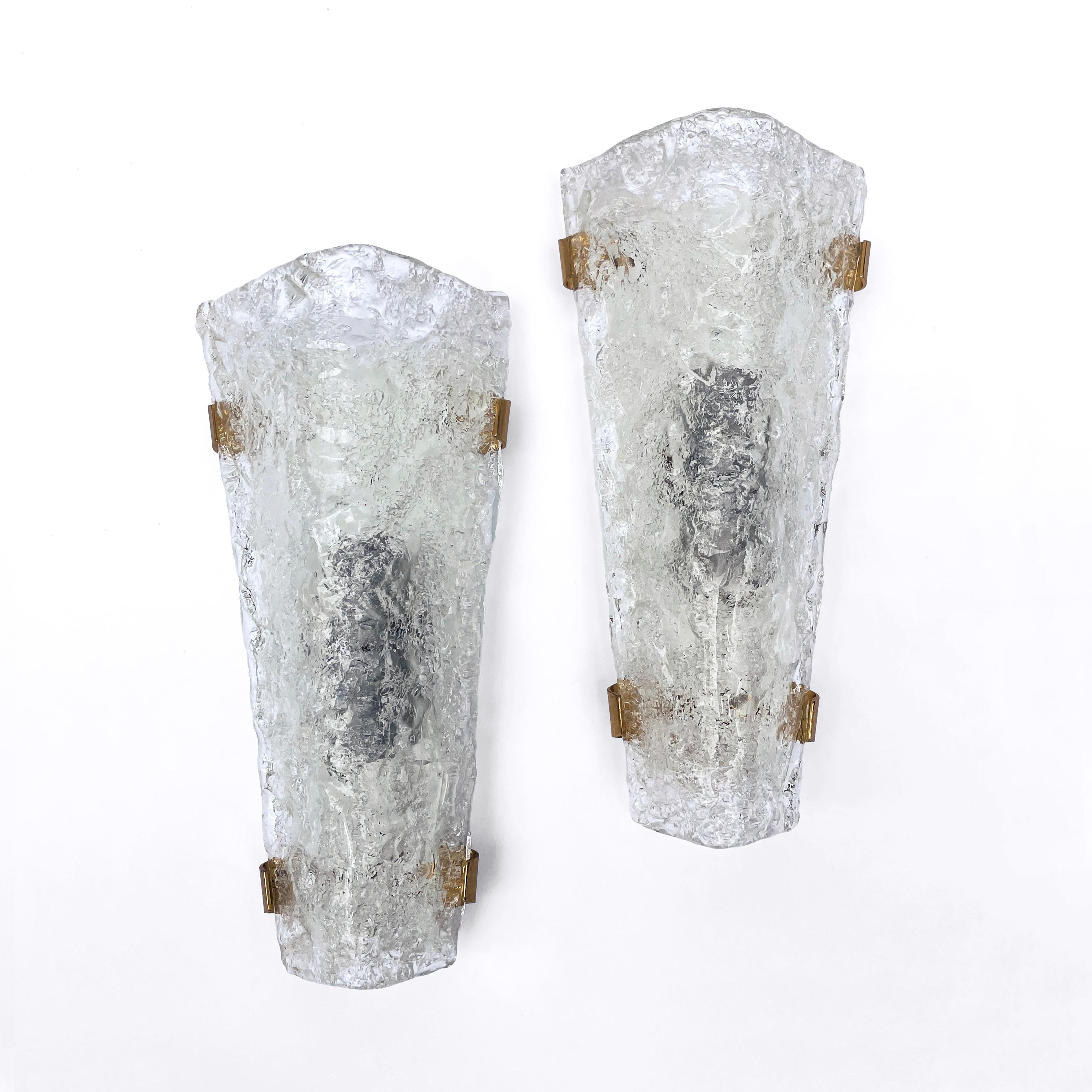Lovely vintage mid century set of two ice glass wall lights wall sconces by Ernest Igl and manufactured by Hillebrand Leuchten in the 1960s.
The wall lights are made of thick angular glass and are each held in place with four brass fittings. The ice