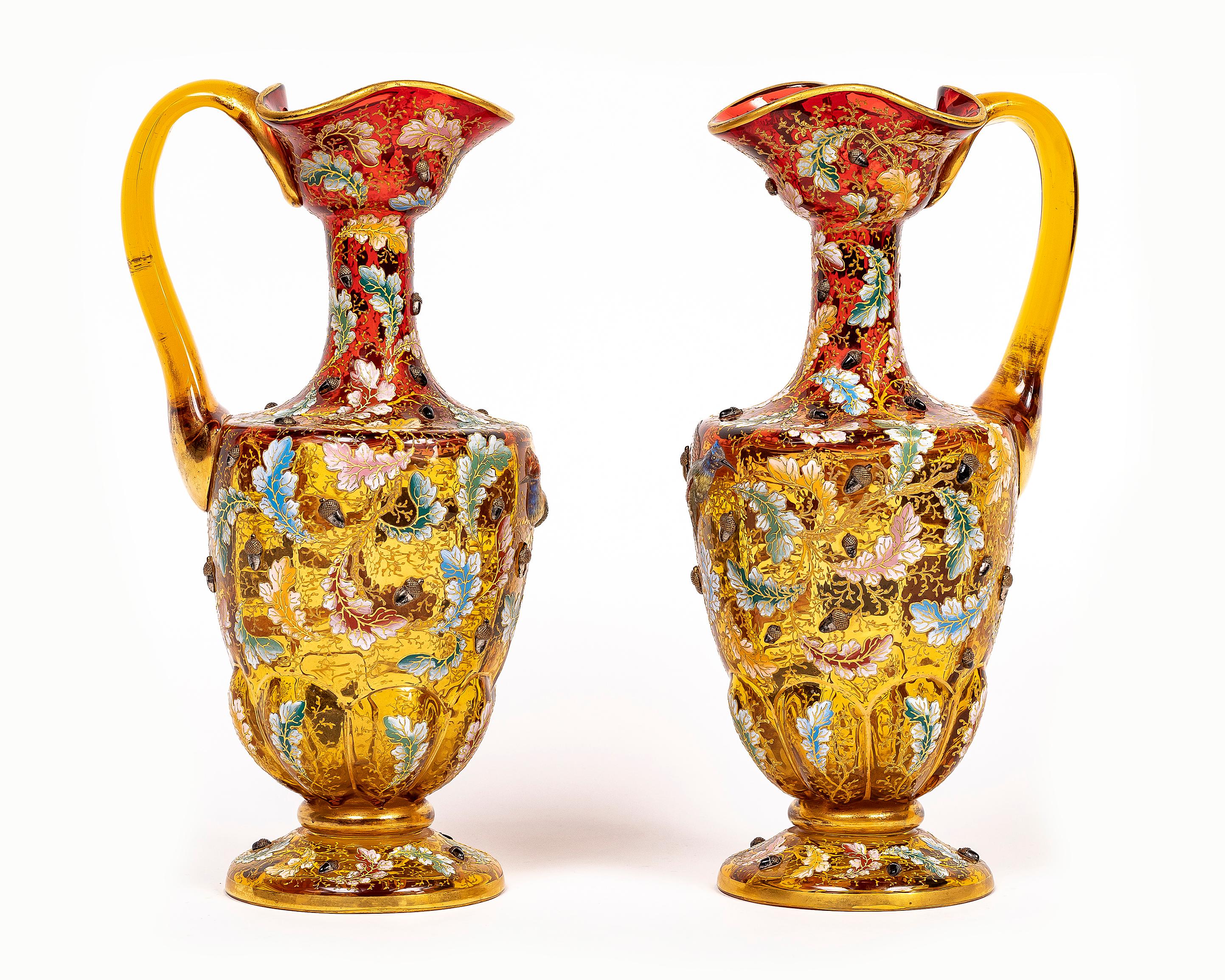 An Incredible, Large, and Rare Original Pair of 19th Century Moser Ruby Red Crystal Enameled Gilt Pitchers/Ewers/Vases with Applied Enamel Parrots, raised Acorns, Enameled and Gilt Surface Leaves. Of pinched quatrefoil form with a ruffeled top, in