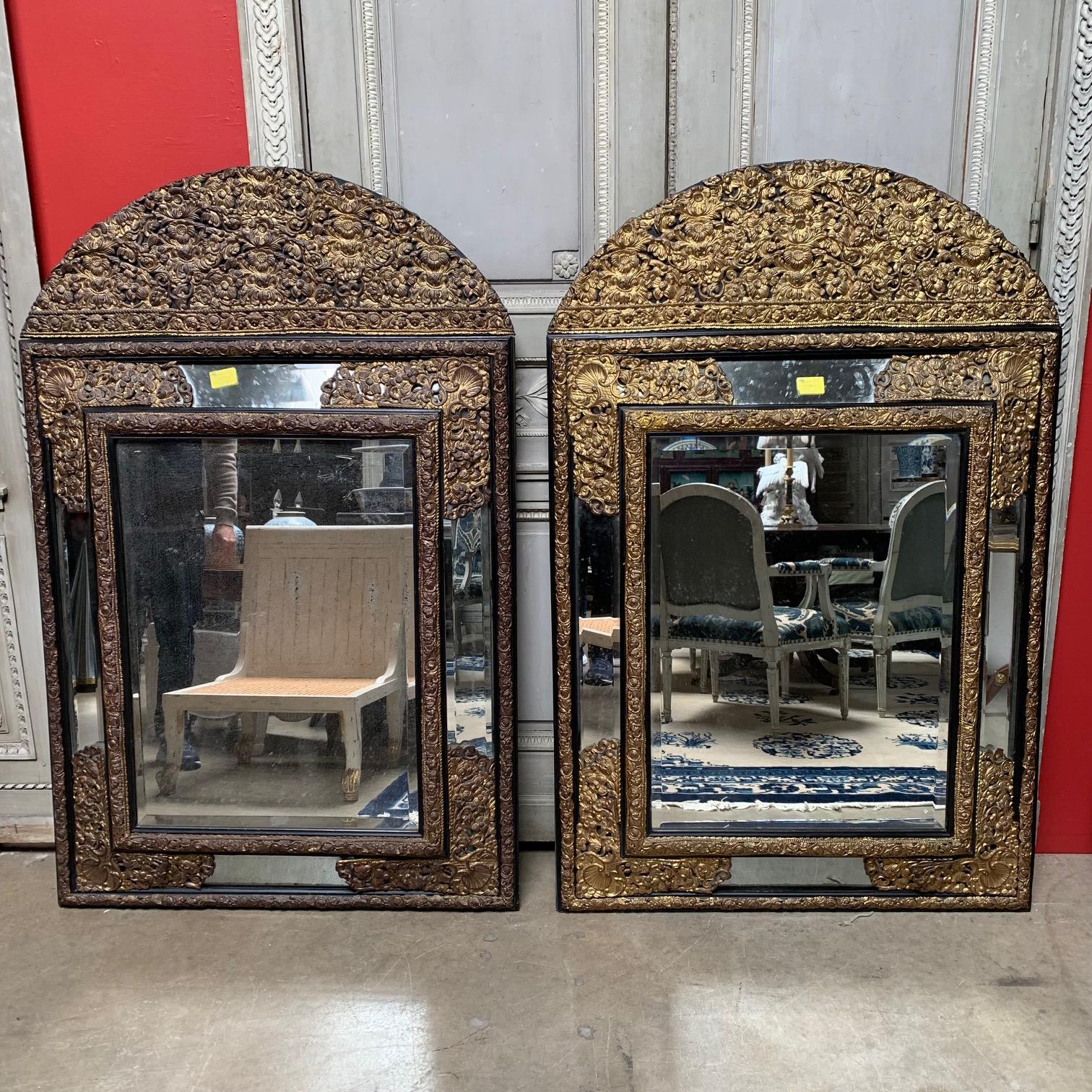 Une grande paire de miroirs français en repousse dans le style Régence datant de la fin du 19ème siècle. Ces miroirs impressionnants sont magnifiquement réalisés et sont en vieil état. Le travail du laiton sur l'un des miroirs conserve encore une