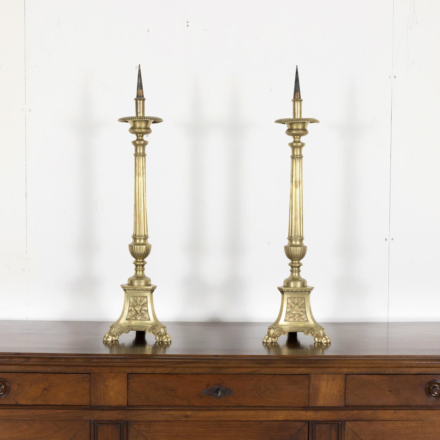 Ein schönes Paar französischer Kathedralaltarpritschen oder Kerzenhalter aus massivem Messing des 19. Jahrhunderts aus Südfrankreich bei Montpellier, um 1880. Jede steht auf drei Klauenfüßen mit dreieckigen Sockeln, auf denen die Jungfrau Maria, das