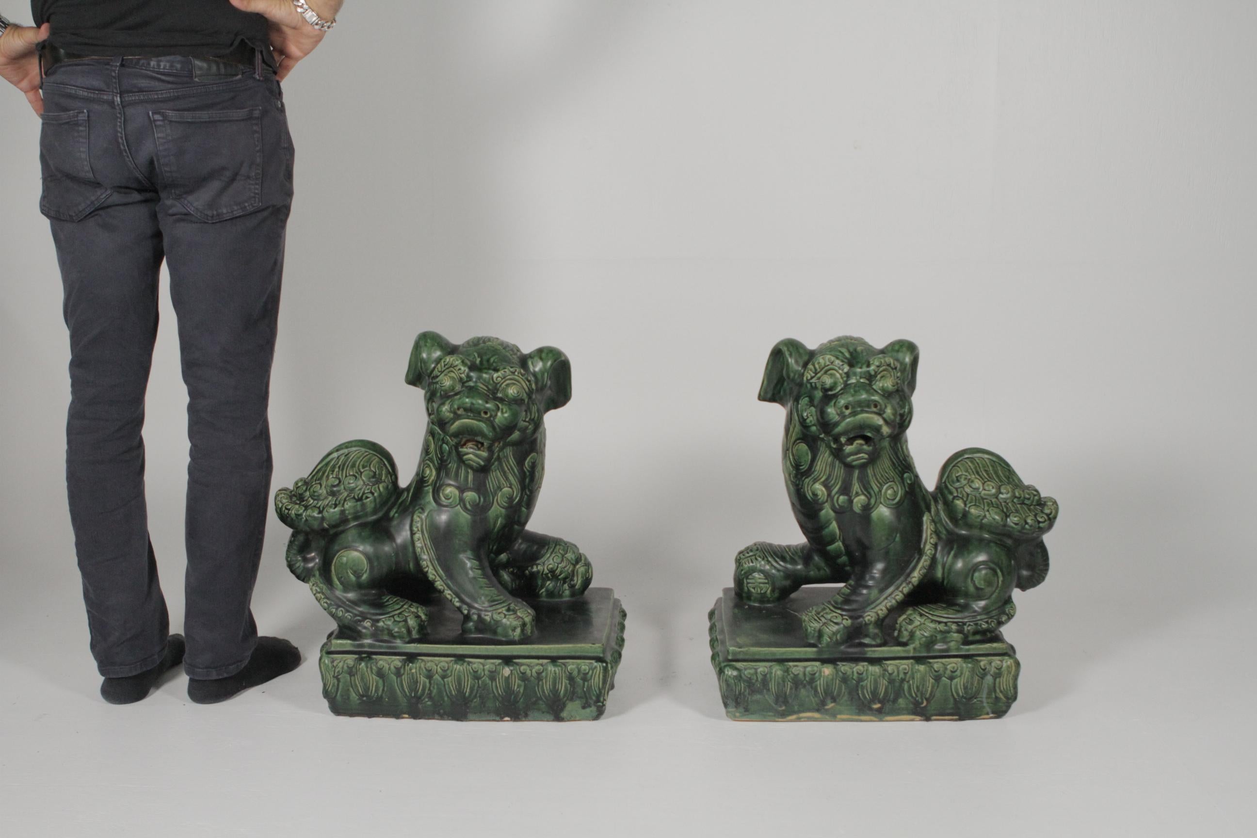 A large pair of 19th century green glazed foo dogs. The rare vibrant green glaze over heavy dense pottery, one is the male, the other female, a mirror image and true original pair.
