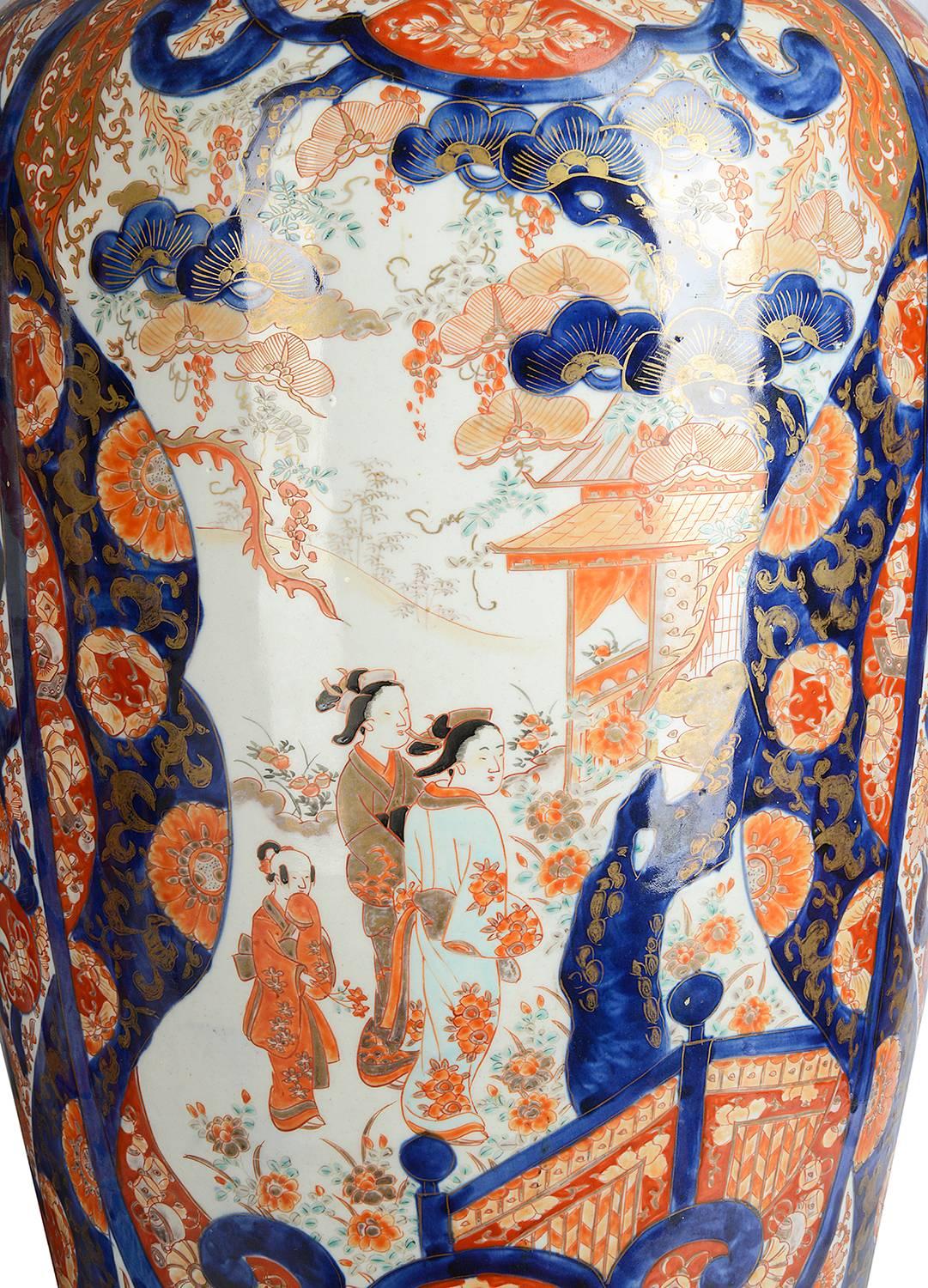 A large and impressive good quality pair of 19th century Japanese Imari vases, each having classical motifs, flowers and scrolls to the ground and inset painted panels depicting women and children in the gardens.