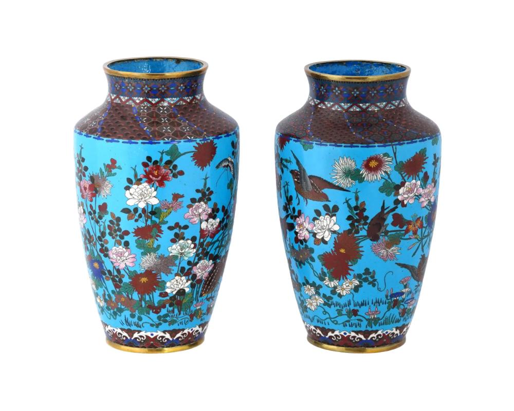 A pair of large antique Japanese, late Meiji era, enamel copper vases. The urn shaped vases are adorned with polychrome images of birds in blossoming flowers against a bright turquoise background made in the Cloisonne technique. The necks and the