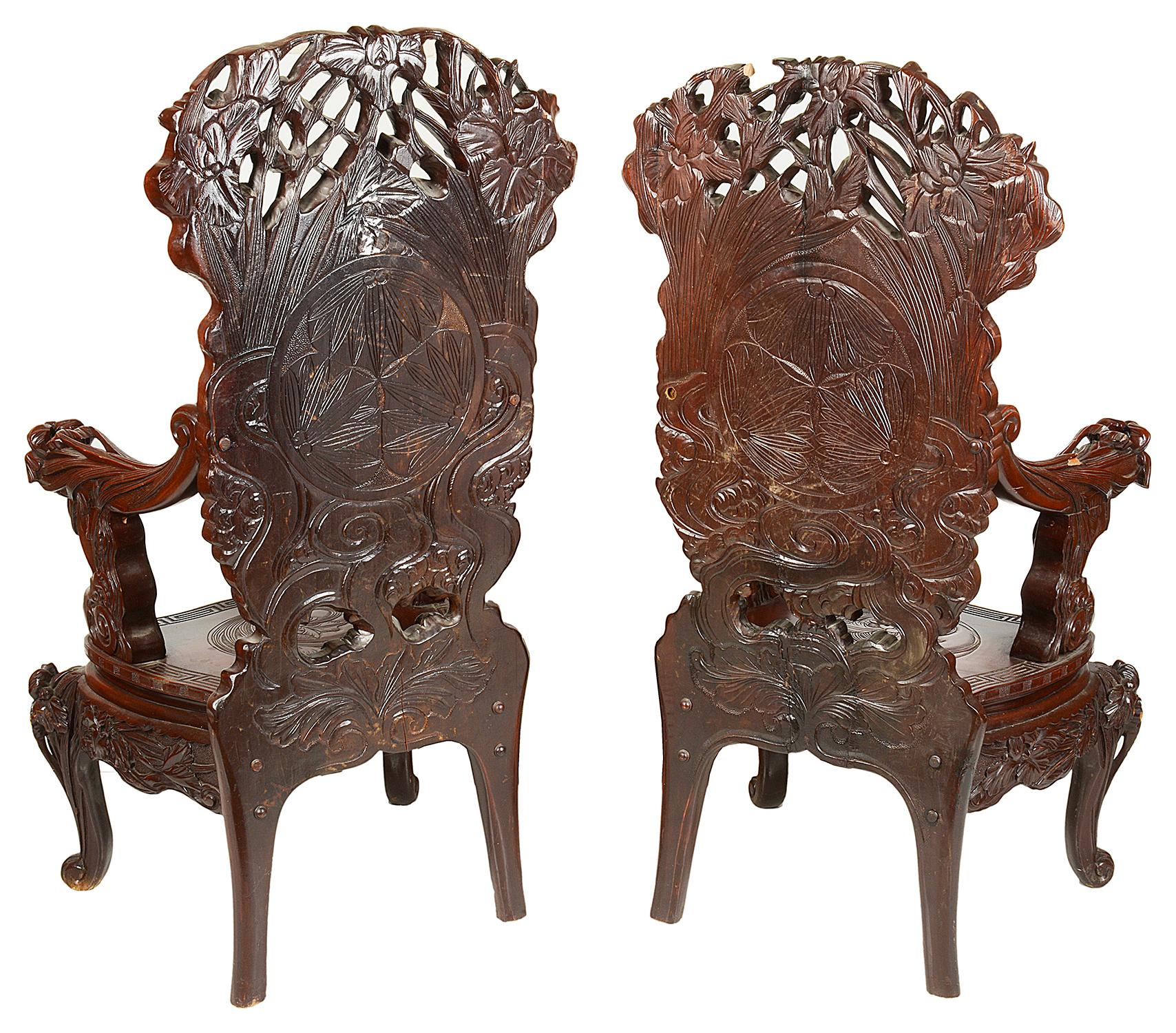 A very impressive large pair of Japanese carved softwood armchairs, each depicting carved exotic flowers and foliage.