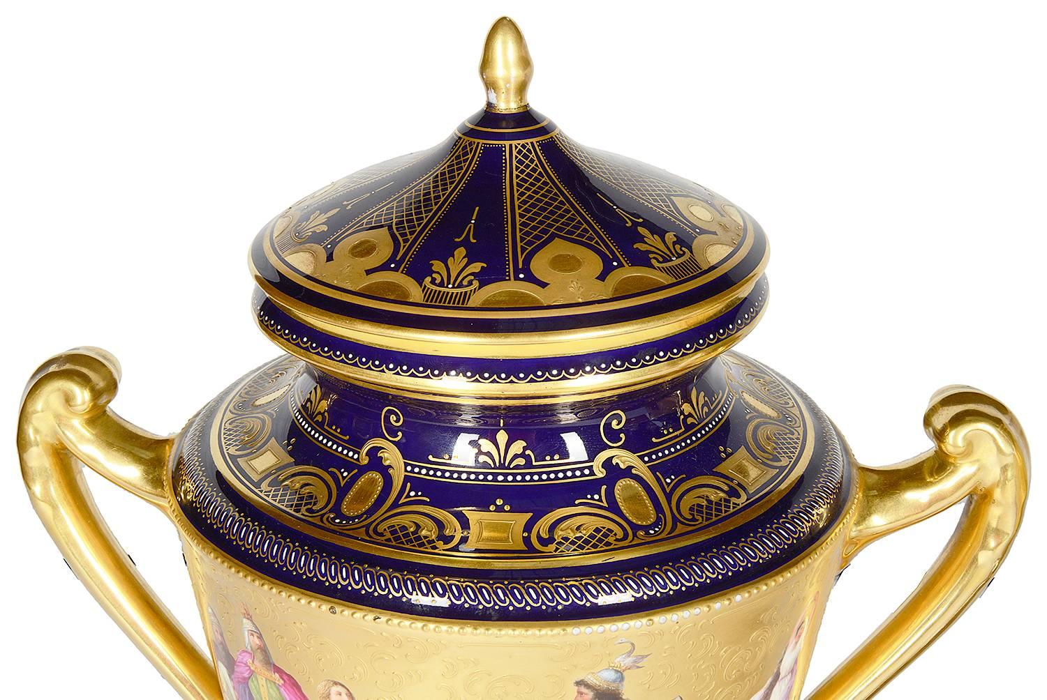A very good quality pair of late 19th century Vienna porcelain lidded urns. Each with a cobalt blue ground, gilded scrolling boarders and romantic classical scenes.