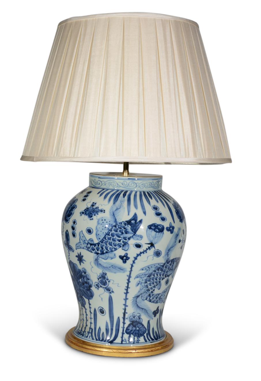 Une belle paire de vases balustres chinois bleu et blanc, décorés dans le goût Kangxi dans des tons de bleu sur fond blanc, avec des poissons exotiques dans un paysage aquatique, maintenant montés comme lampes avec des bases tournées dorées à la
