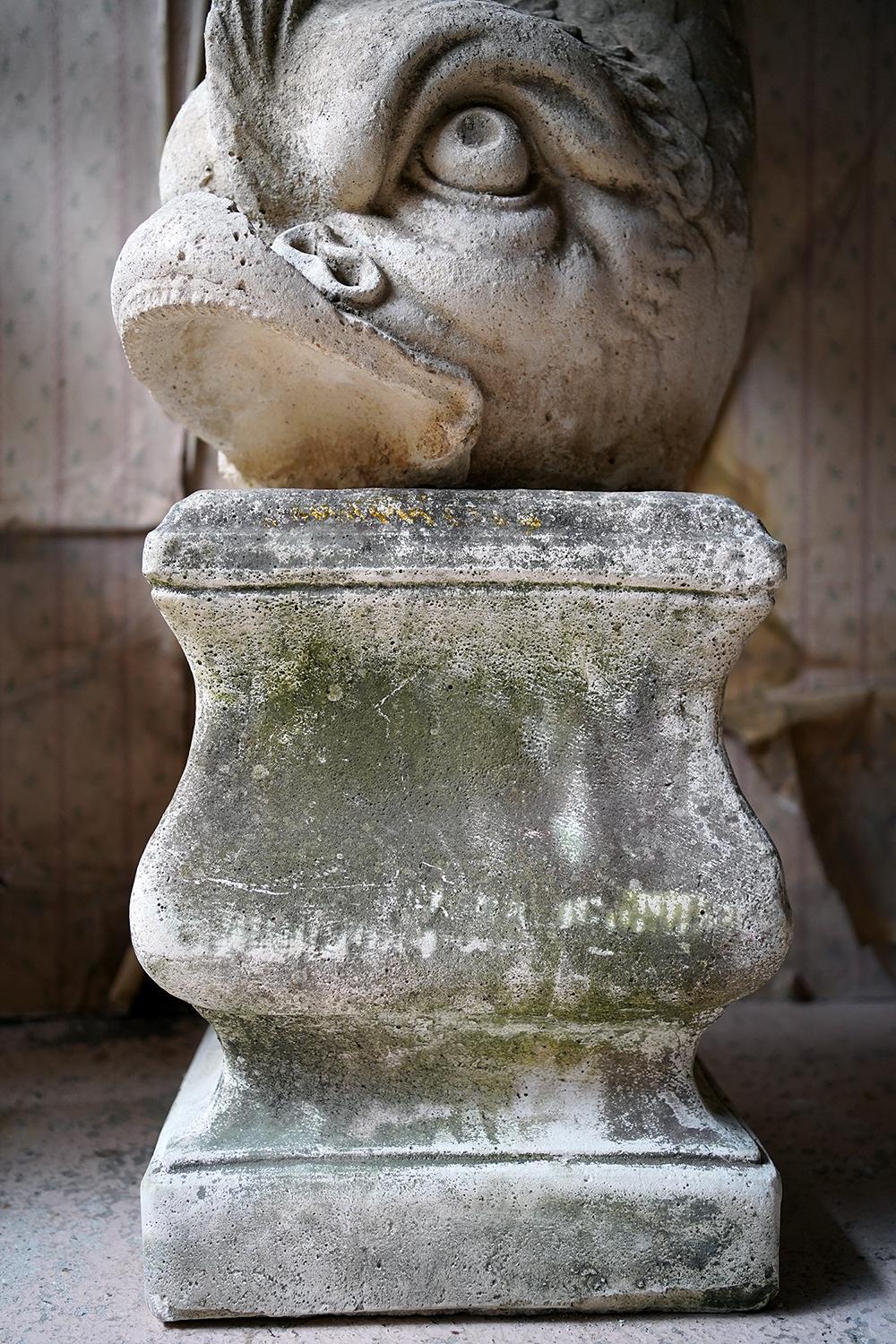 The large and imposing pair of cast composition stone opposing dolphins, standing at around four and a half feet high on the plinths, the designs after Felix Austin originals of the 1830s, one being painted green, and each standing on bombe shaped