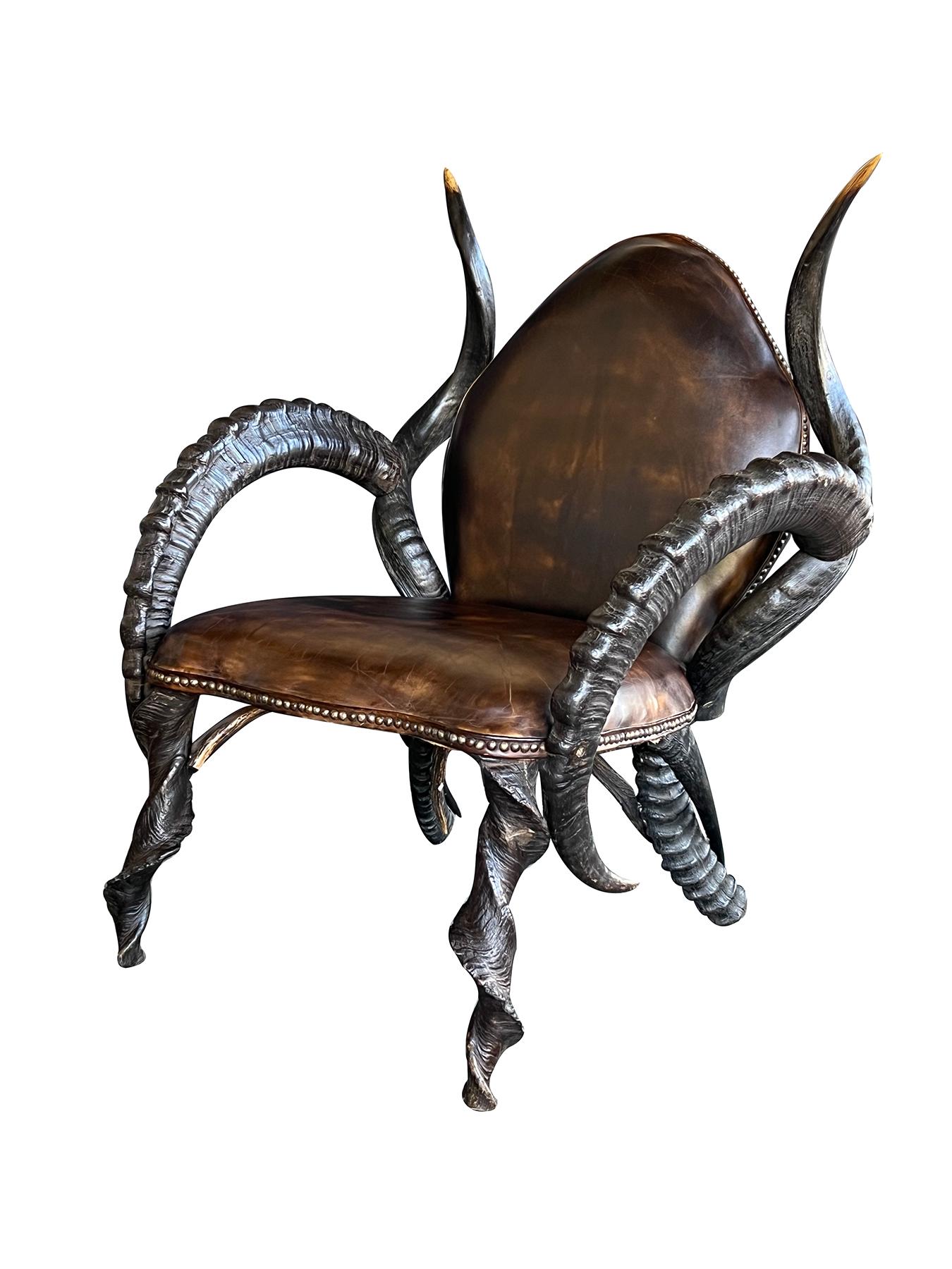 an impressively large pair of horn chairs constructed of antelope horn of various sizes; the arching leather upholstered back flanked by spiraling horns joining a similarly upholstered seat flanked by boldly-scaled curved arms; all over shapely horn