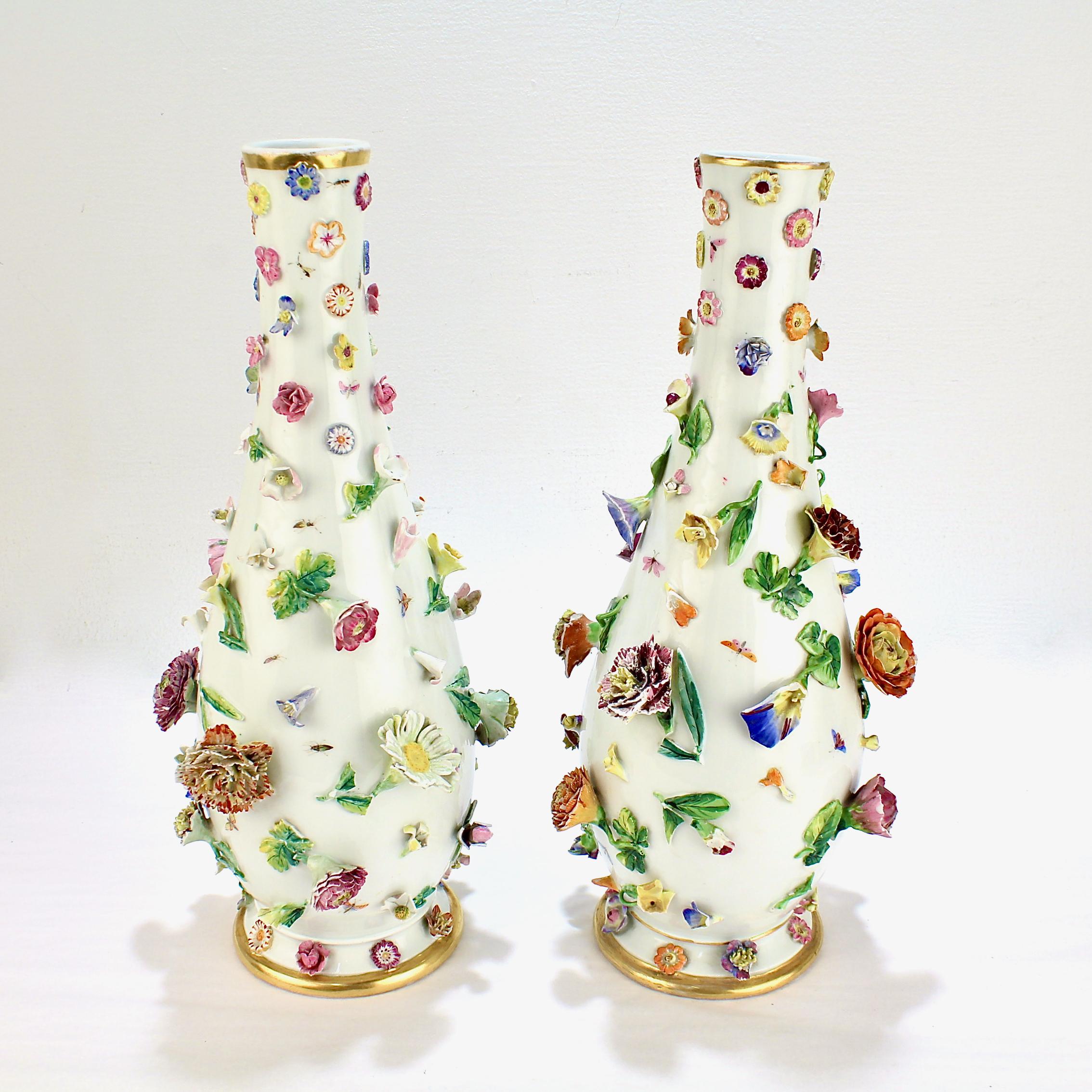 A fine pair of large antique Meissen porcelain vases.

Each encrusted throughout with figural porcelain flowers. Hand Painted insects & butterflies can be found between the foliage throughout. 

Both the base and rim of each vase have gilt