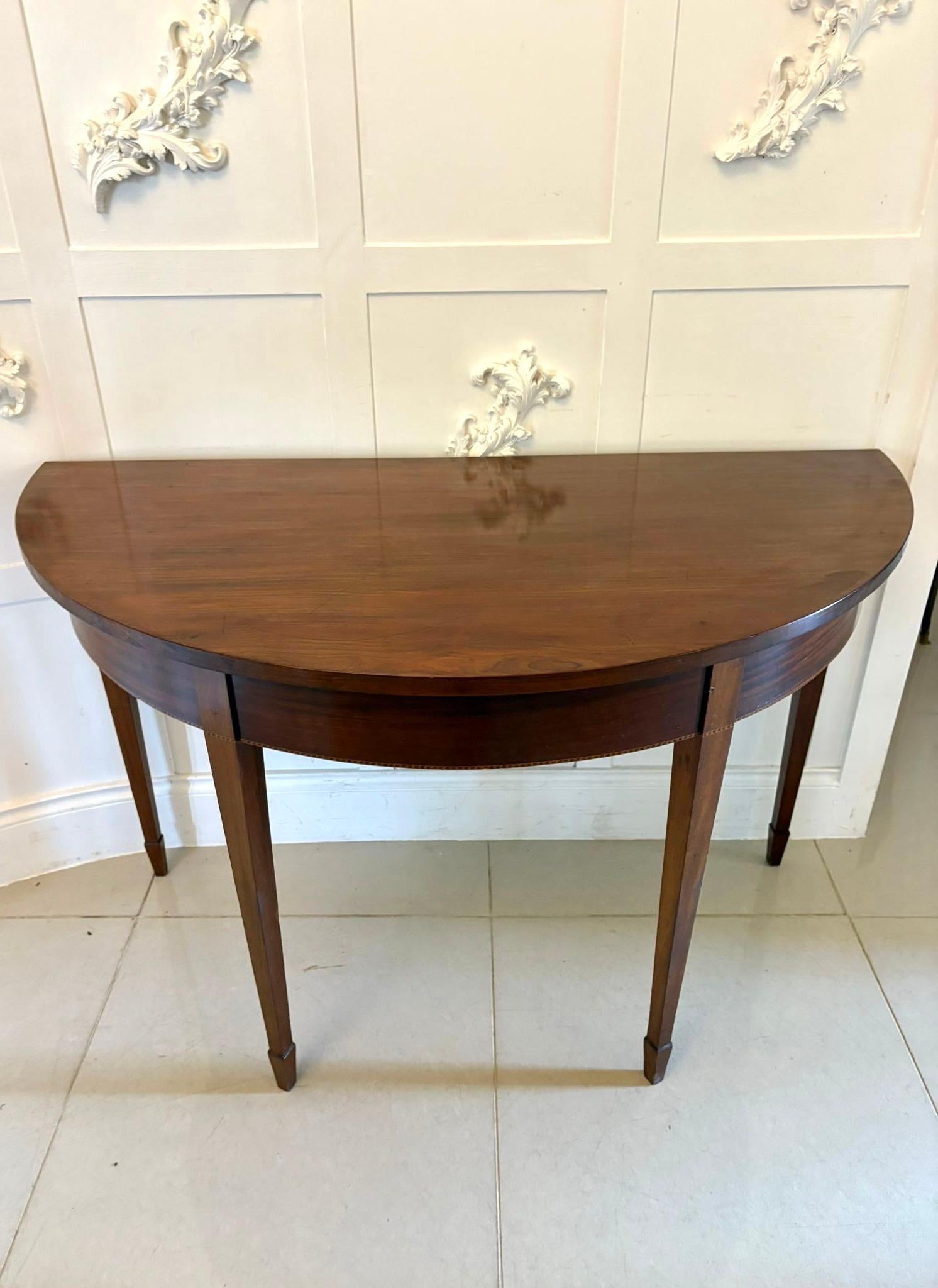 Large pair of antique George III quality figured mahogany demi lune shaped console tables having a quality figured mahogany demi lune shaped top above a demi lune shaped inlaid frieze standing on four elegant square tapering legs with spade feet.

A