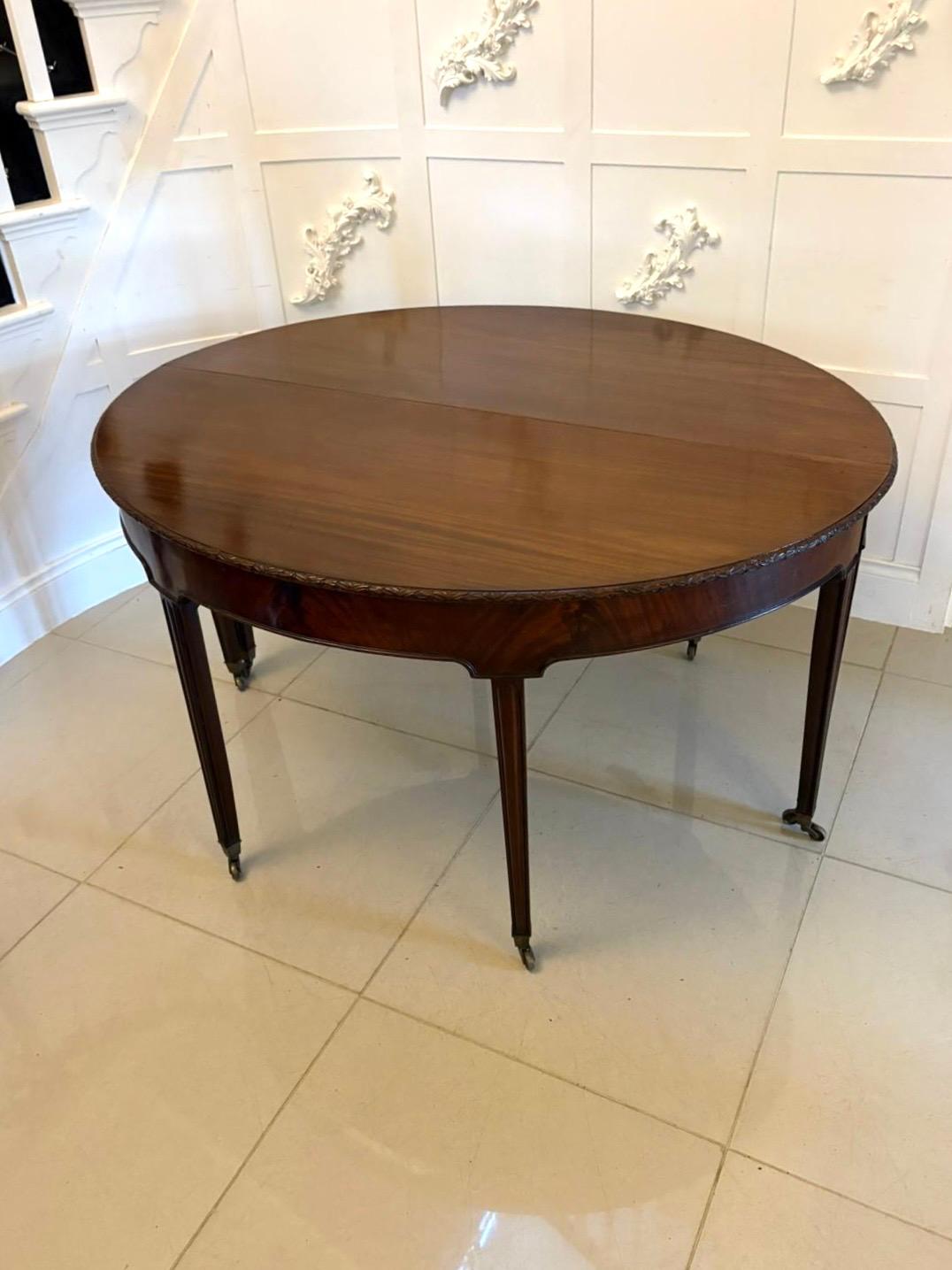 A fine large pair of antique mahogany demilune console tables each table features a beautifully figured mahogany top with a delicate carved edge, raised on elegant fluted tapering legs that terminate in brass castors for easy movement.

The pair can