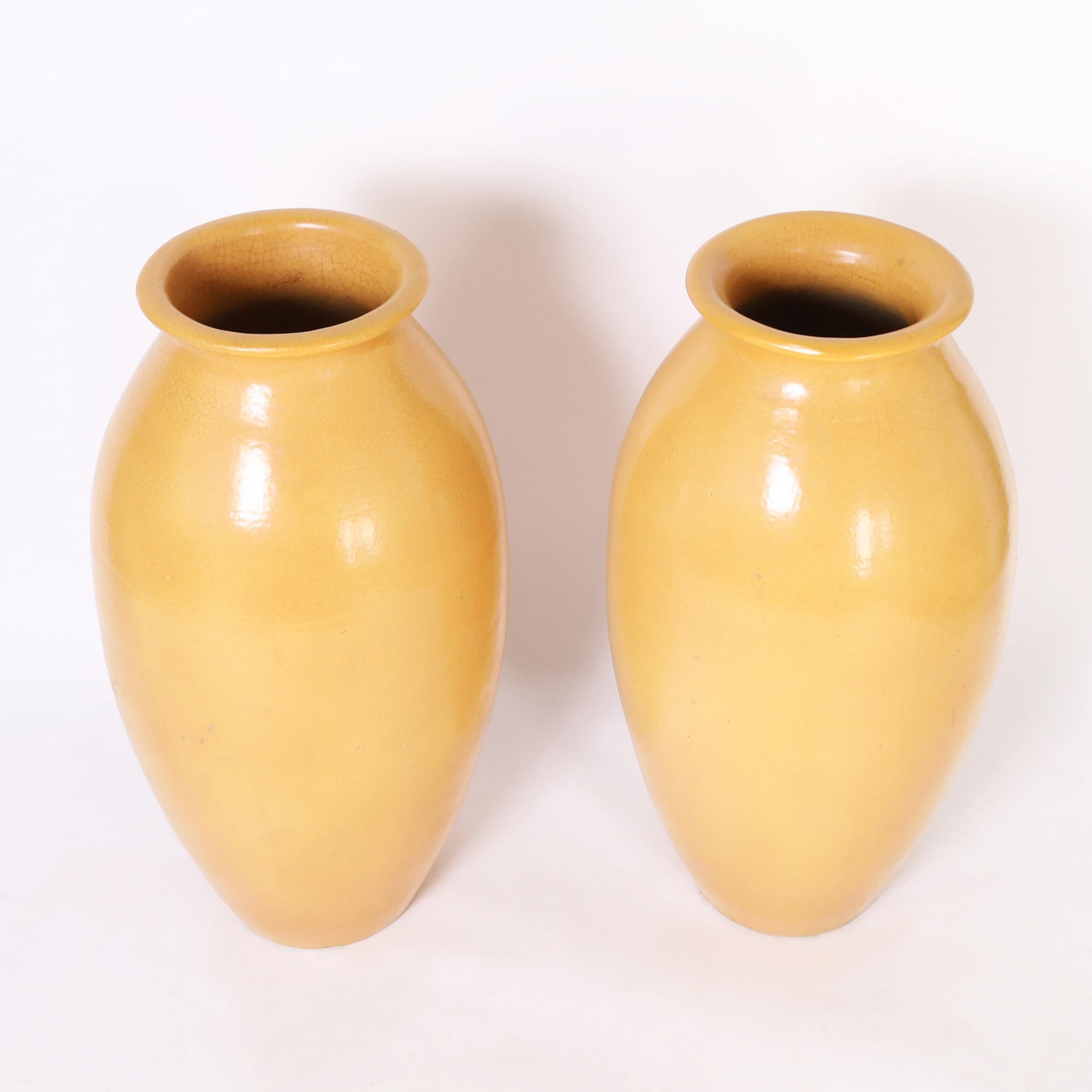 Impressive pair of architecturally interesting French jardinieres hand crafted in terra cotta in a bold scale with classic form having an alluring yellow glaze.