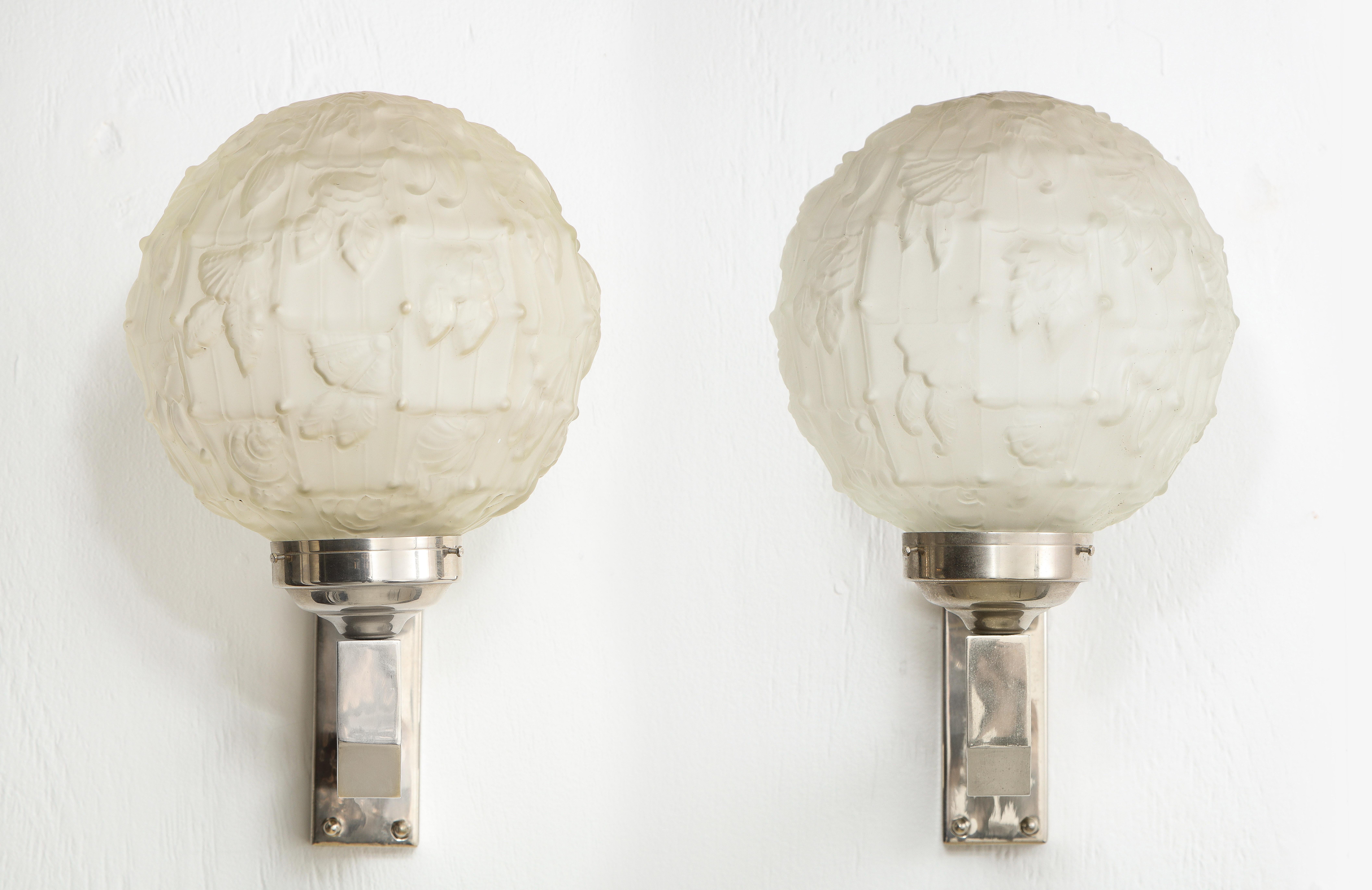 Stunning pair of Art Deco sconces in nickel-plated bronze, the globes are of cast glass and most likely the work of Maison Petitot or Sabino. 2 pairs and a single are available, priced as pairs.