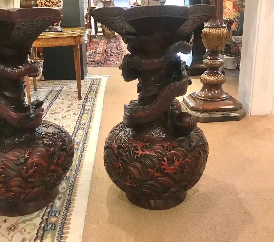 Mid-20th century Chinese carved hardwood and lacquered urns. Highly detailed, deeply carved surface with dragons around the centers. The tops in a fluted octagonal shape. Some age cracks which have been sealed.