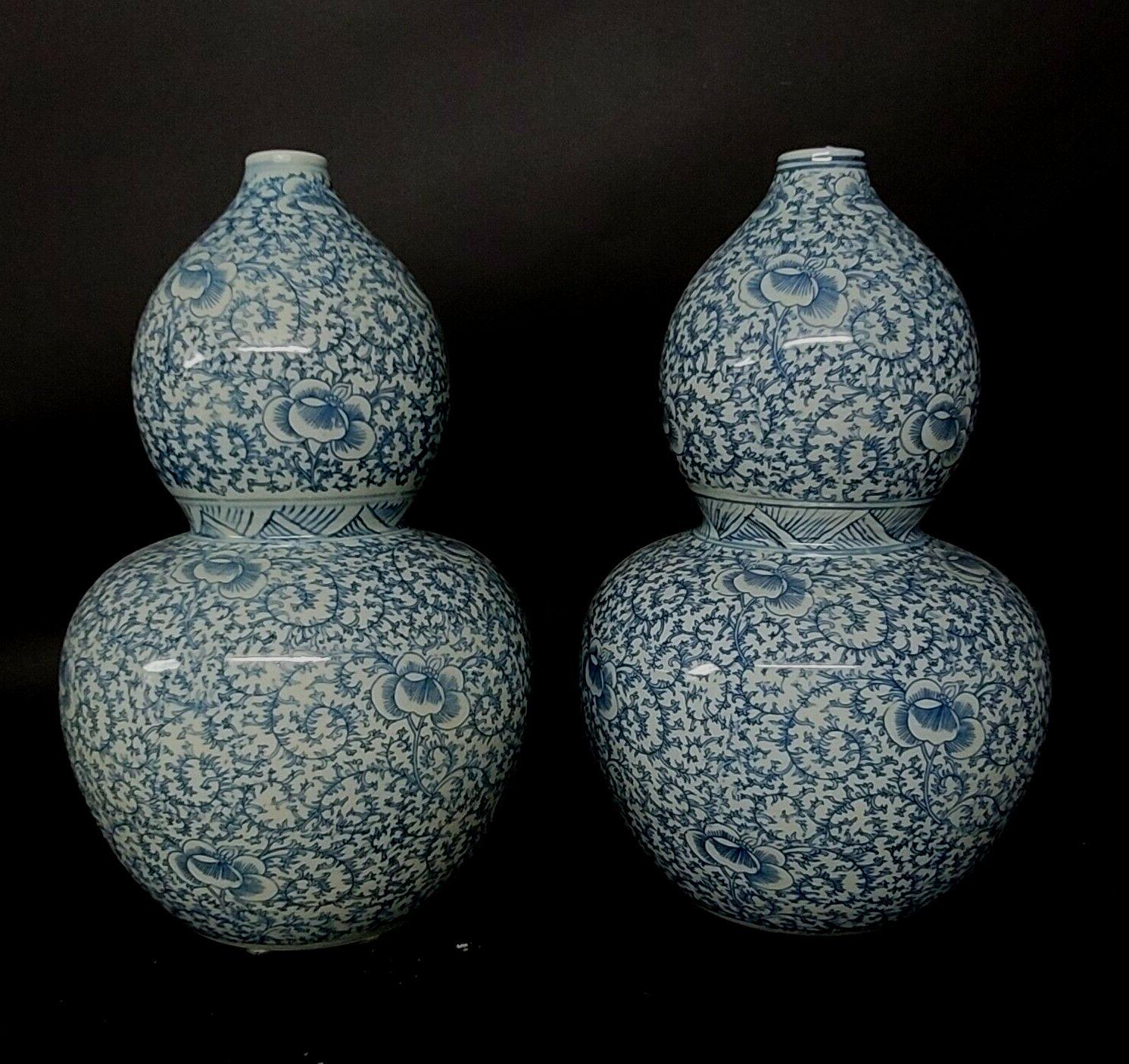 Large pair of blue and white Chinese double gourd vases decorated with flowers and scrolling foliage.

