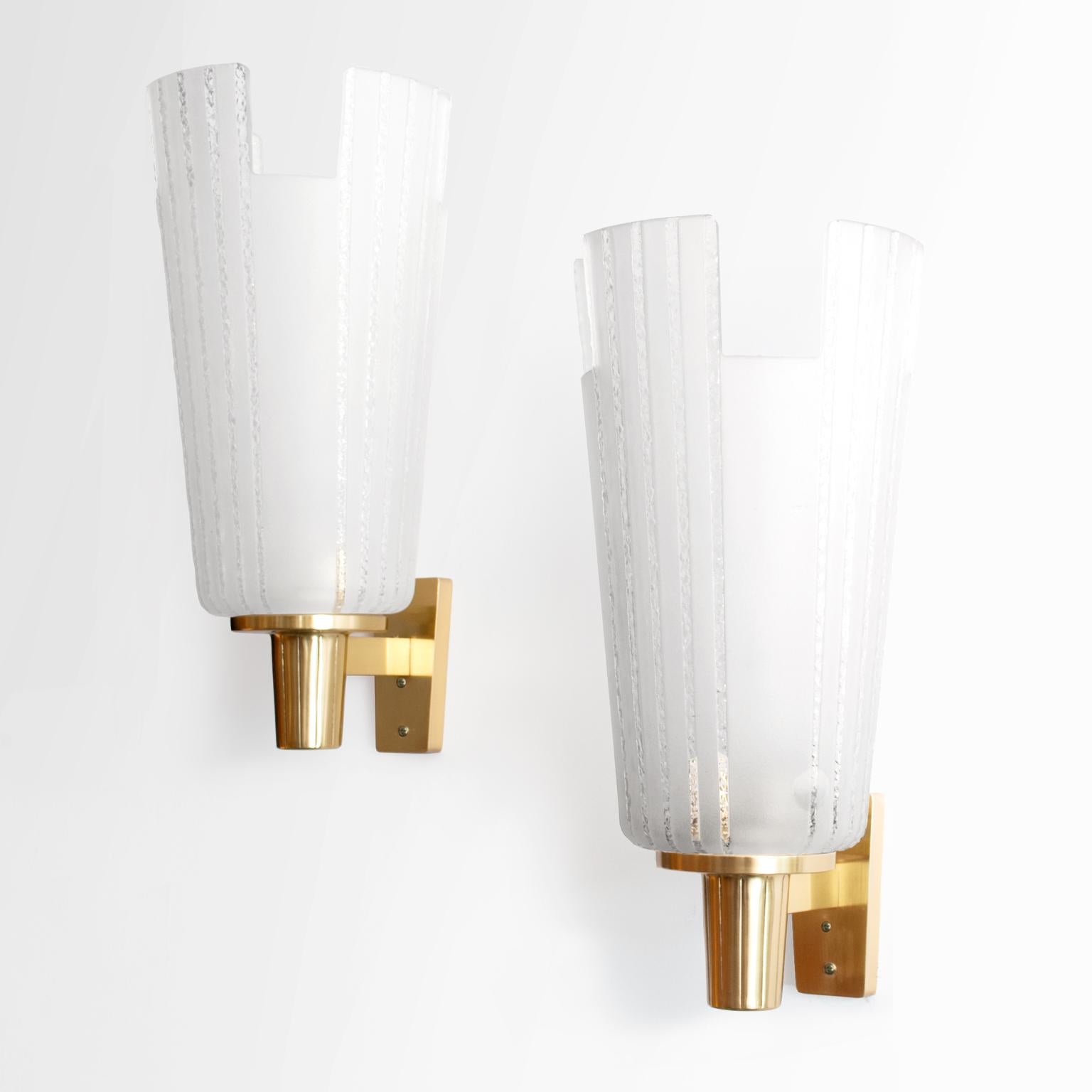 Large pair of Scandinavian Modern single arm sconces from Böhlmarks with sand blasted glass shades manufactured at Pukeberg's Glassworks, circa 1938. Each sconce has a glass shade with notched sections along the top and a polished brass arm