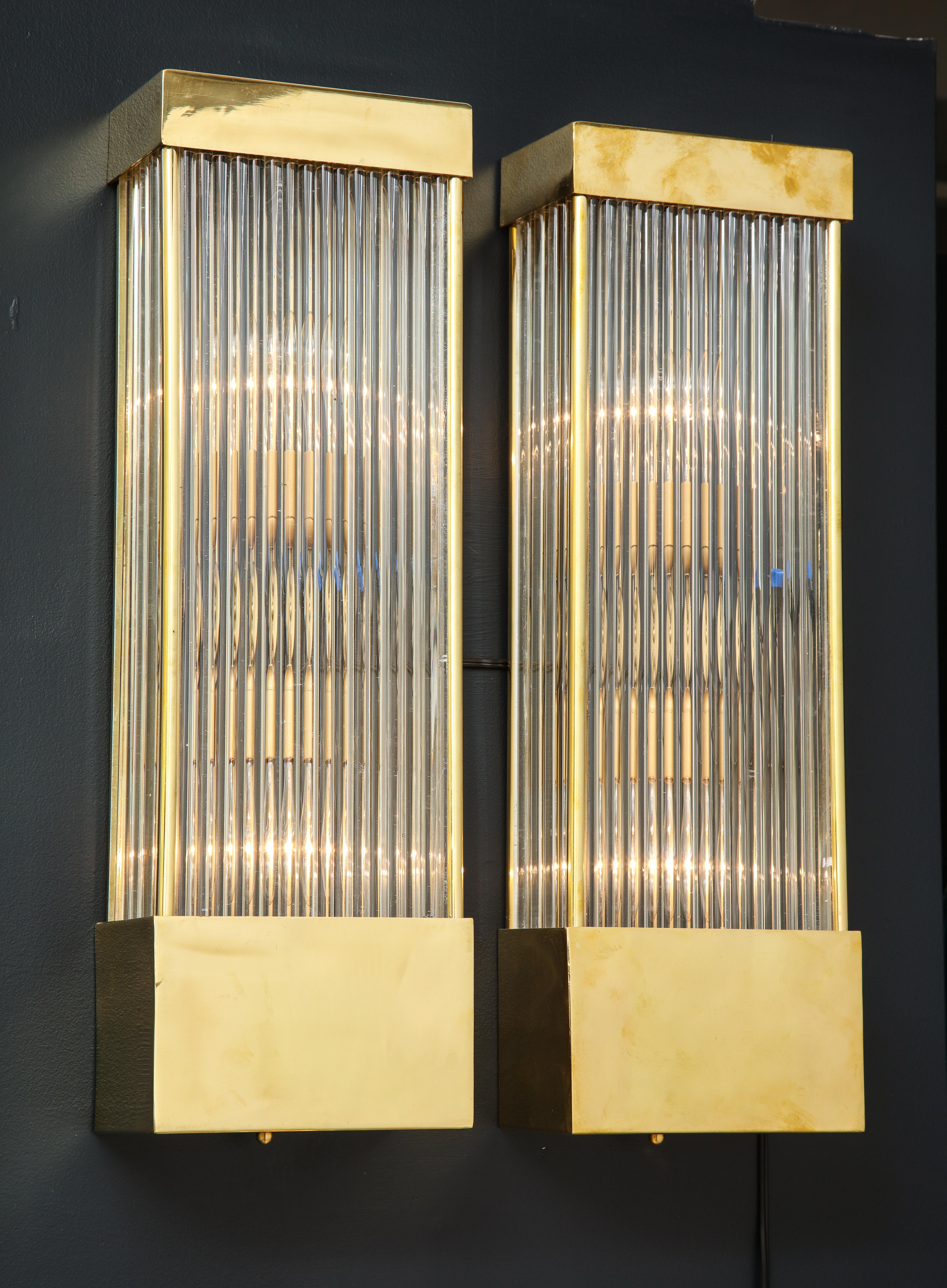Large pair of clear Murano glass rods with brass frame rectangular sconces.  Hand-casted, narrow, clear glass rods form the body of these sconces which are held together by the brass rectangular caps on each end. When lit, the glass rods reflect a