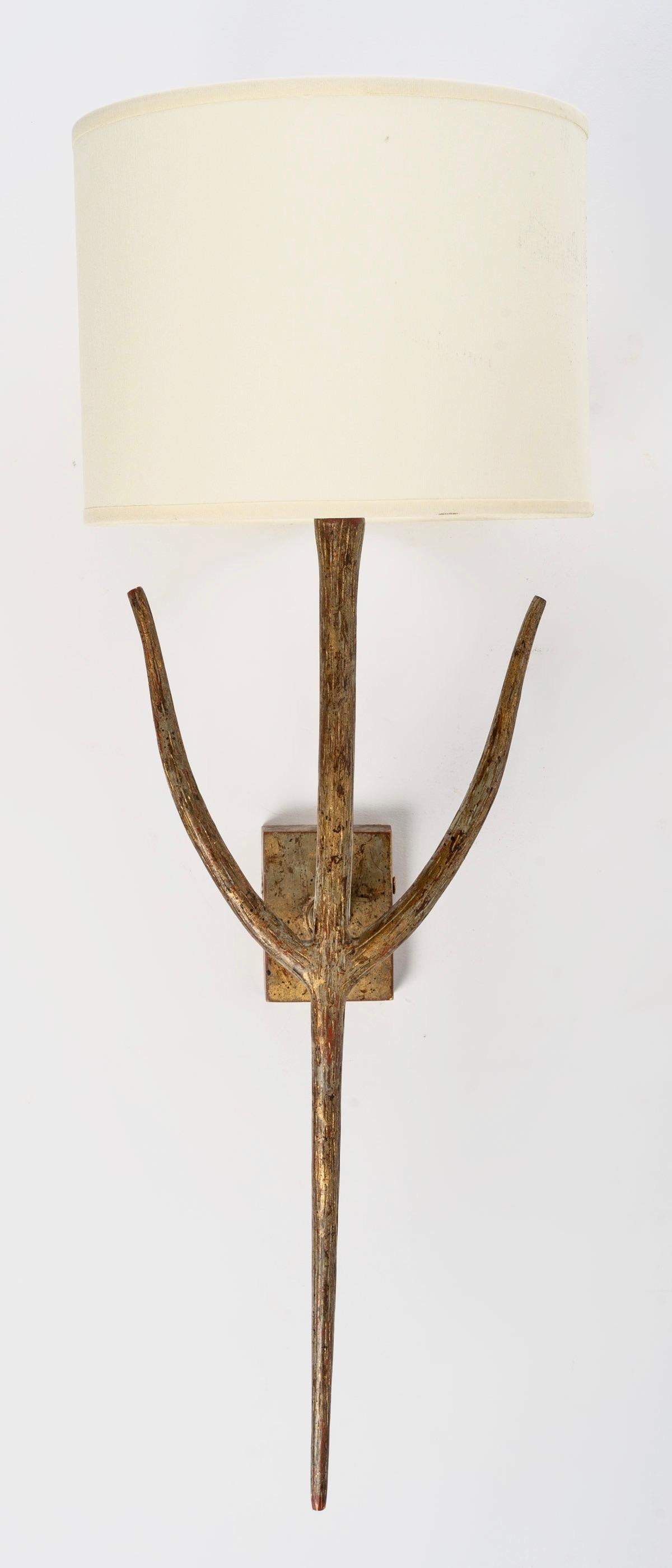 The wall lights are in bronze with a nuanced patina imitating a ribbed branch.
Composed of a luminous central arm adorned with two small branches on either side of the wall lamp and dressed in a
Off-white cylindrical shade.
The central arm rests