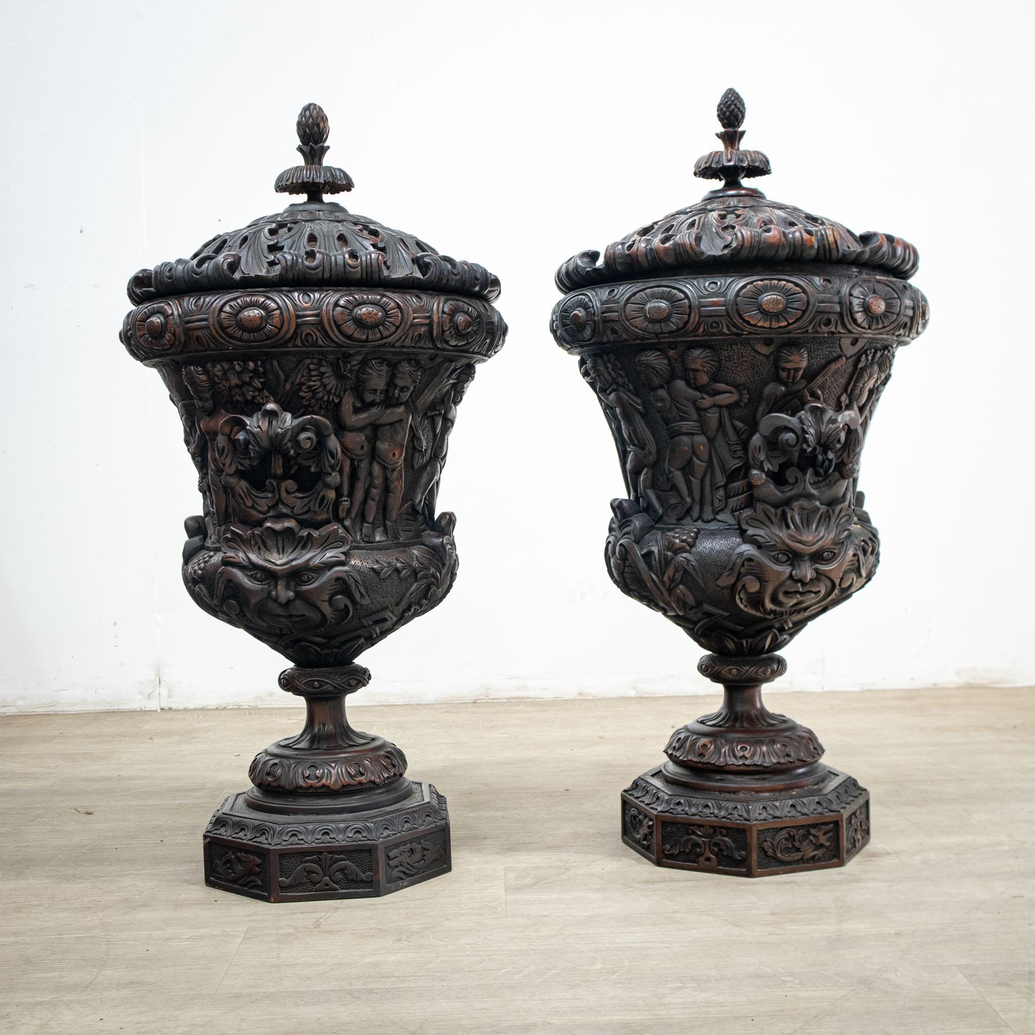 A fabulous pair of heavy carved mahogany table urns with their lids, these are in dark wood which has a burnished appearance giving them the look of bronze from a distance.

– Wonderful weight, with removable lids topped by pine cone shaped