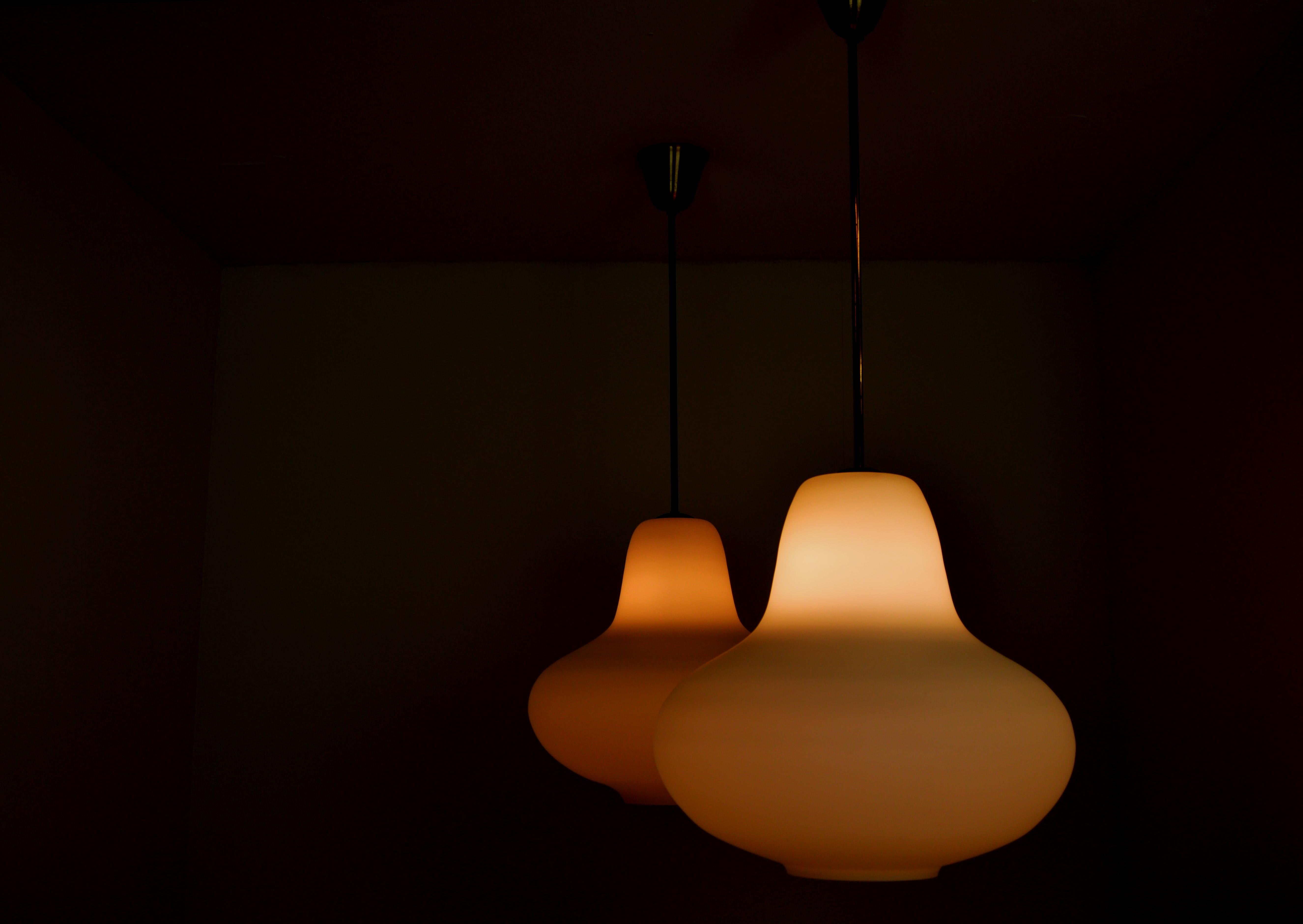 A rare pair of ceiling lamps designed by Carl-Axel Acking, Sweden, during the 1950s. 
Pear shaped opaline glass. Brass details. Scandinavian Modern / Swedish modern design.