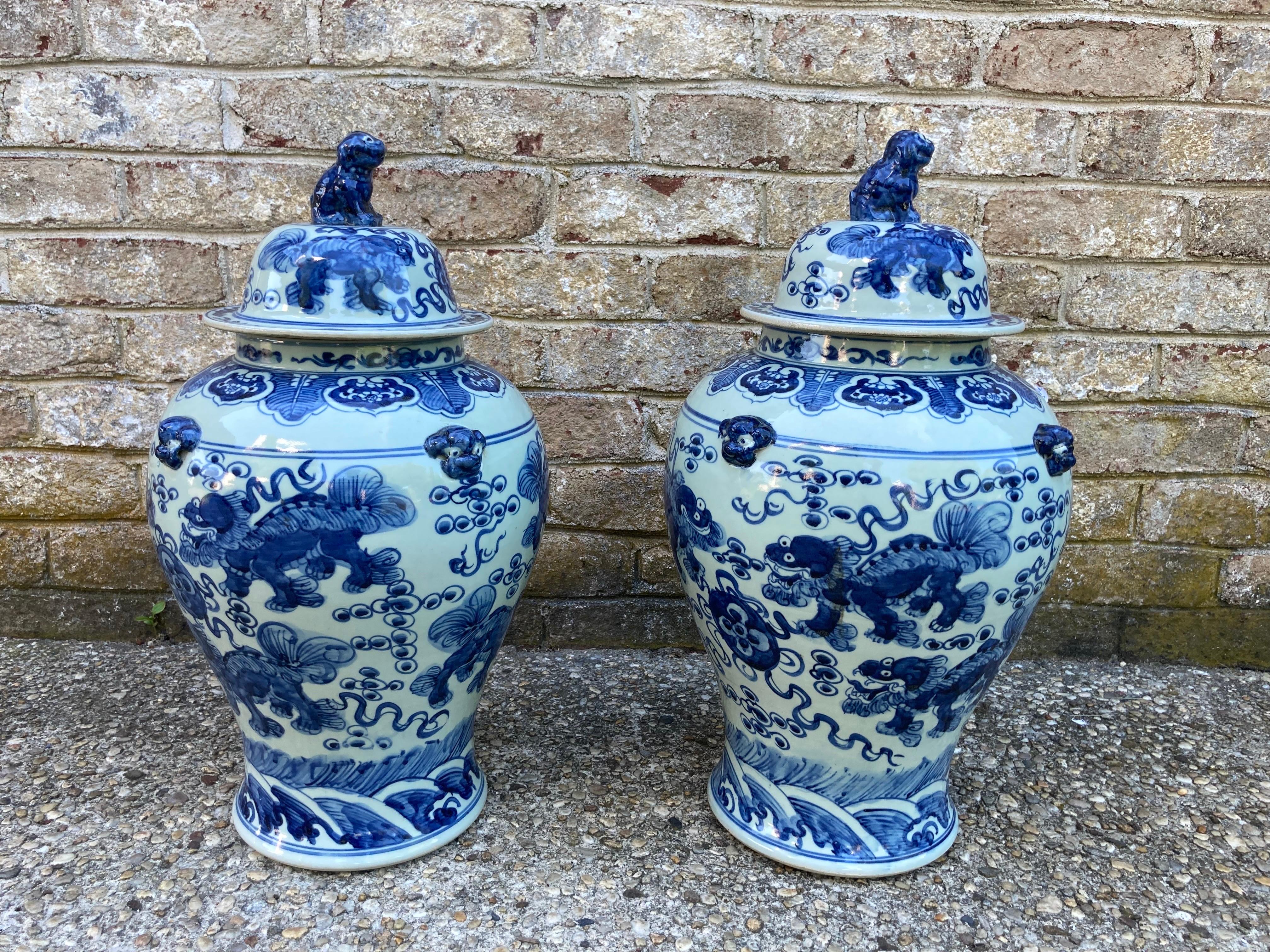 Great pair of Chinese blue and white jars with lids...... foo dogs painted on the sides of the jars as well as figures on the lids.... 