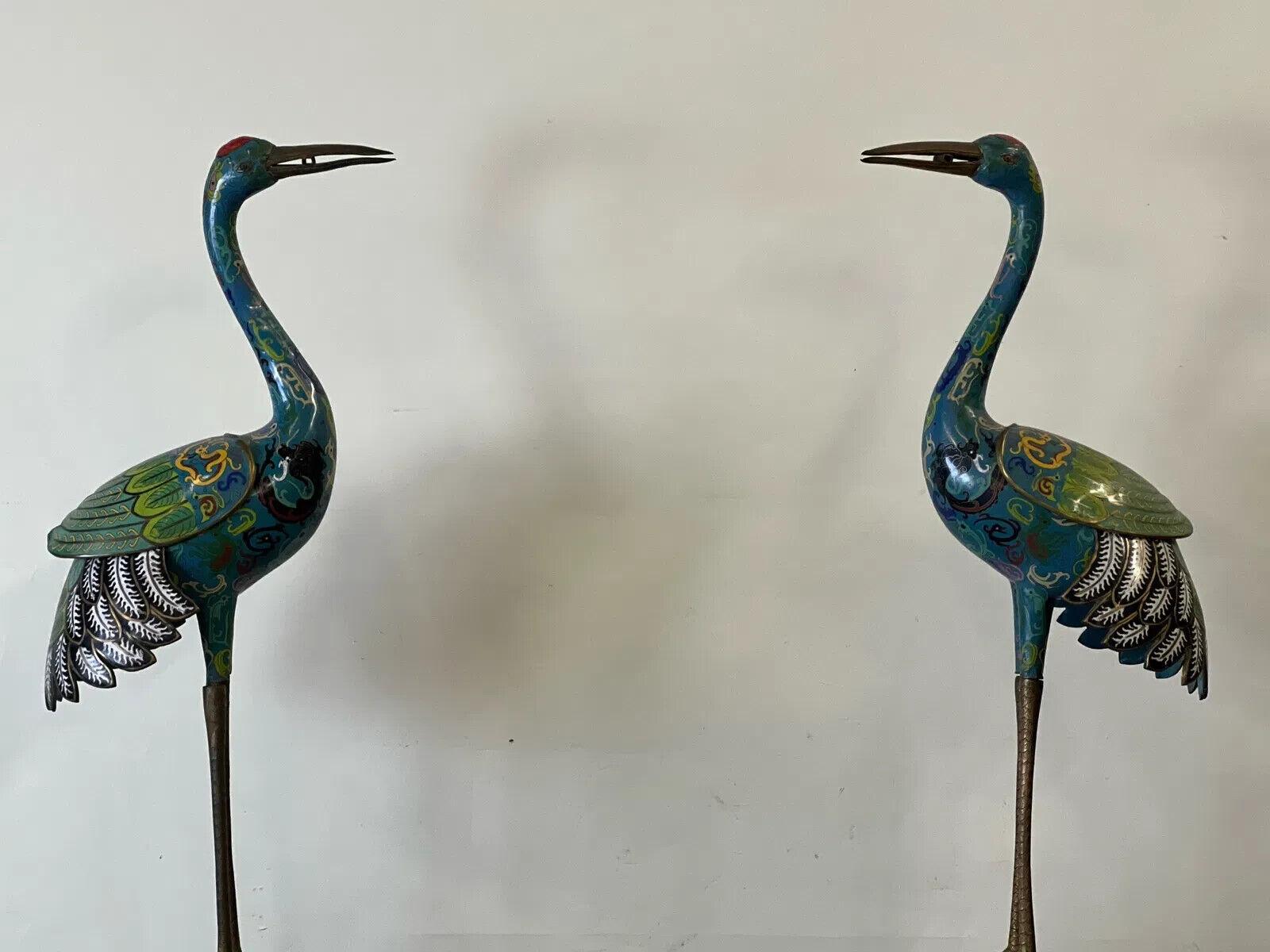 A large pair of Chinese cloisonné sculptures of cranes. The cranes are detachable at their legs, and are mounted on later circular pedestal bases. 40in tall x 14-1/2in wide (excluding pedestals). 55in tall (including pedestal). 

OVERALL GOOD