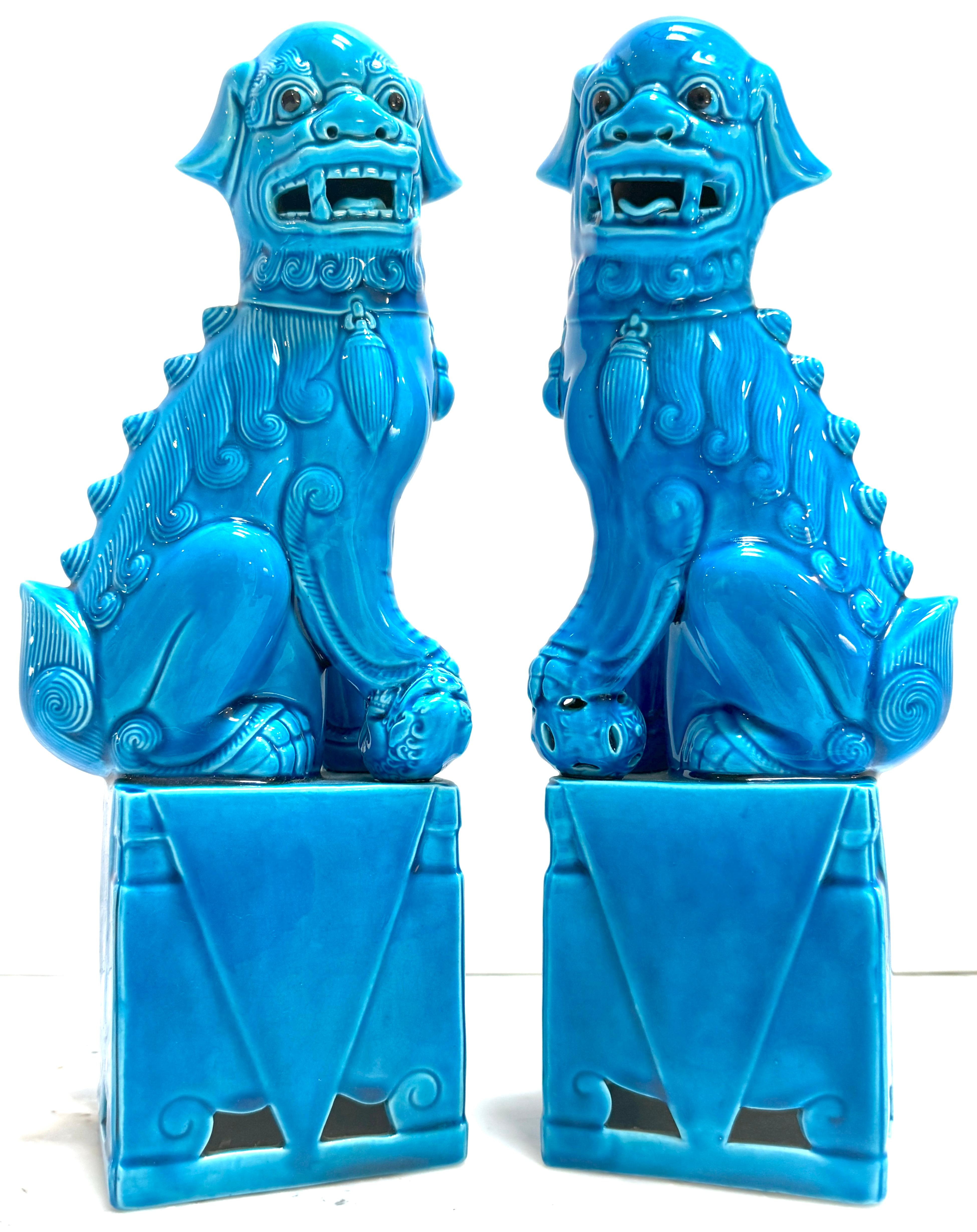 A Large Pair of Chinese Export Turquoise Foo Dogs 
China, 20th century 

This impressive pair of Chinese export porcelain foo dogs, made in the 20th century, highlights exquisite craftsmanship and symbolism. Standing at 12.75 inches high, 5 inches