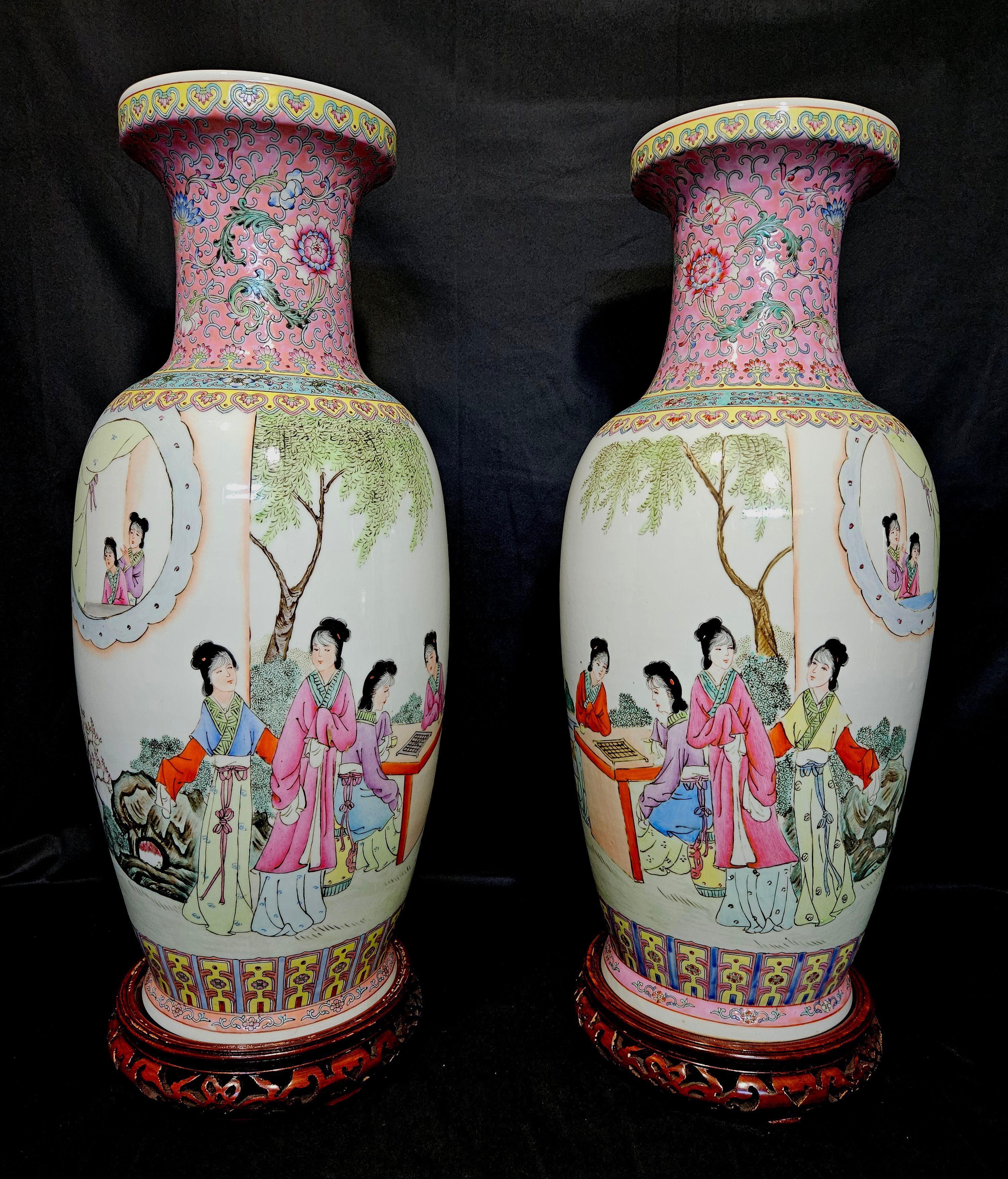 Dies ist ein großes und schönes Paar chinesischer Porzellan Famille Rose Vasen in gespiegelten Bildern, die Damen in einer Gartenszene darstellen, 6-Zeichen-Marke auf dem Sockel, auf den eingebauten Holzständern, aus den 1960er Jahren des 20.