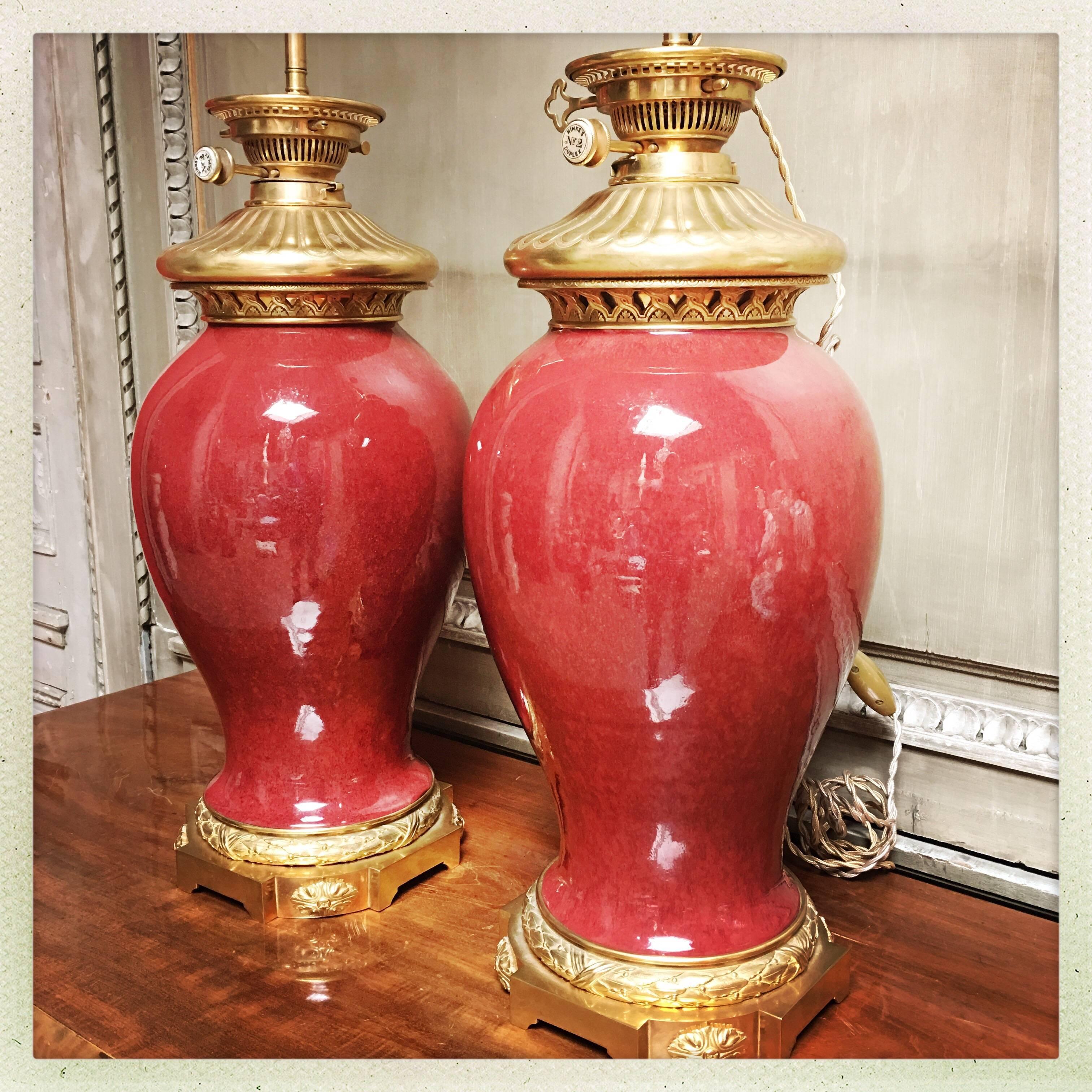 A large pair of Chinese Sang de boeuf (oxblood) porcelain lamp bases with French Louis XVI style bronze dore mountings.
