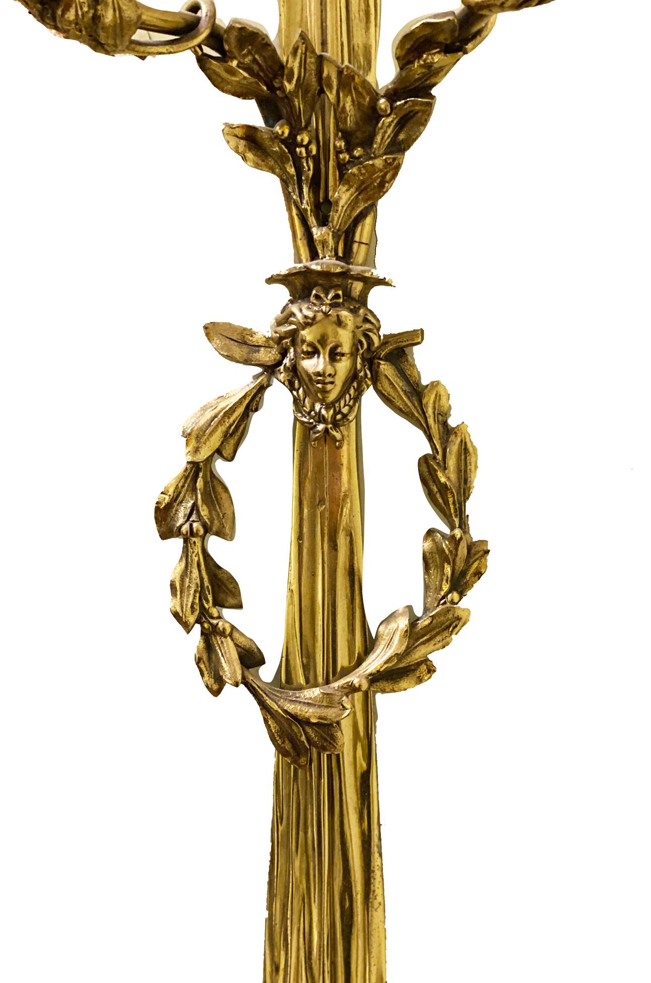 Large Pair of classical ormolu Louis XVI style two branch wall lights having ribbon and foliate decoration and masks to the centre. 