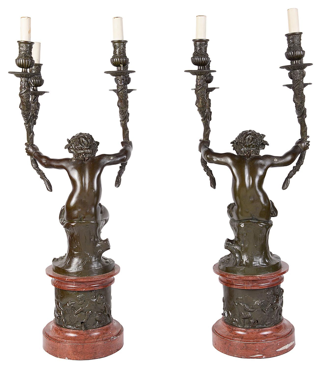 Una coppia di candelabri a due rami in bronzo del XIX secolo di buona qualità, ciascuno con un Putti sorridente con foglie e fasce di testa d'uva, con le braccia distese che sorreggono quattro appliques a forma di ramo, montati su zoccoli in marmo