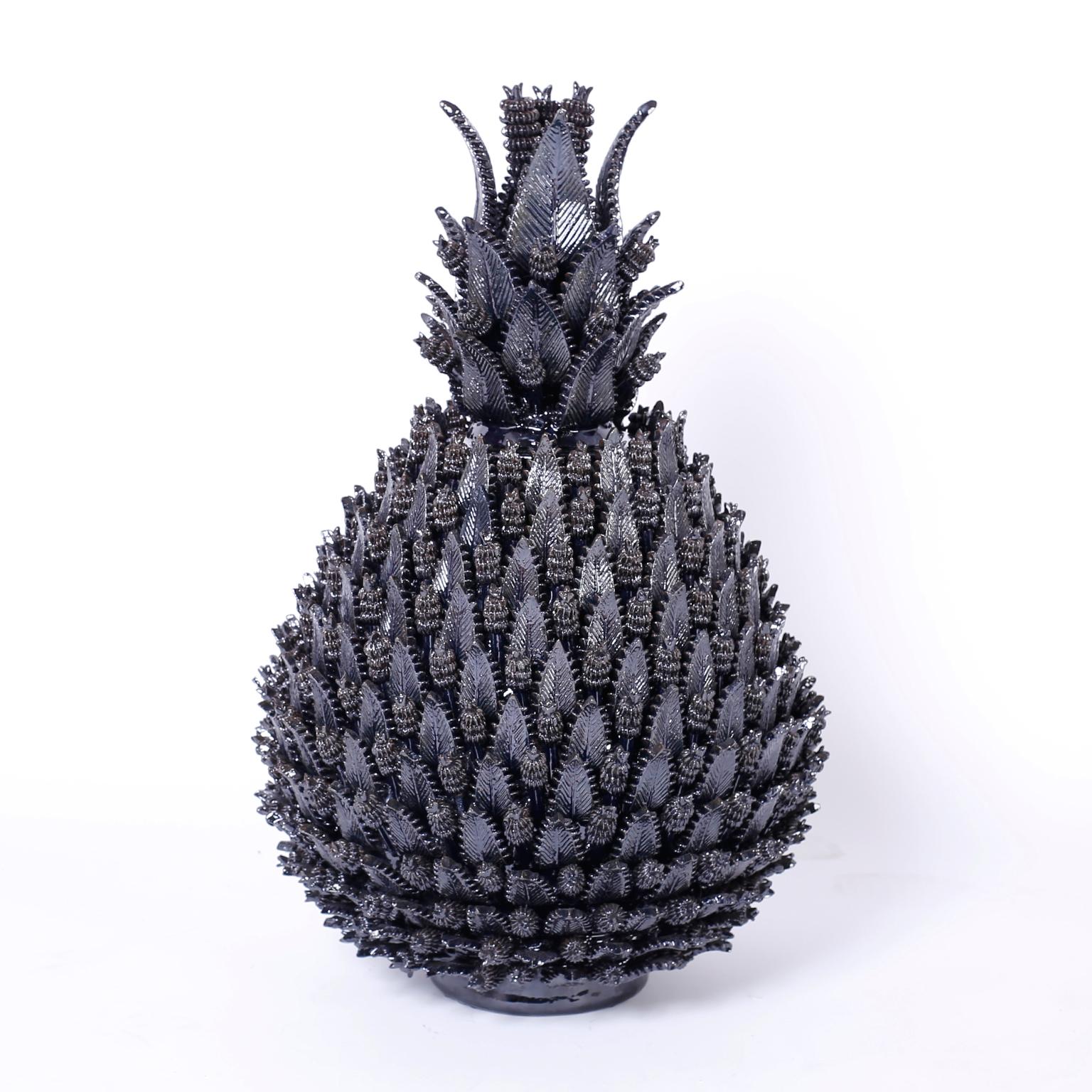 A striking display of pottery prowess with an ambitious composition of leaves and cones forming stylized lidded pineapples covered in a deep inky blue glaze.