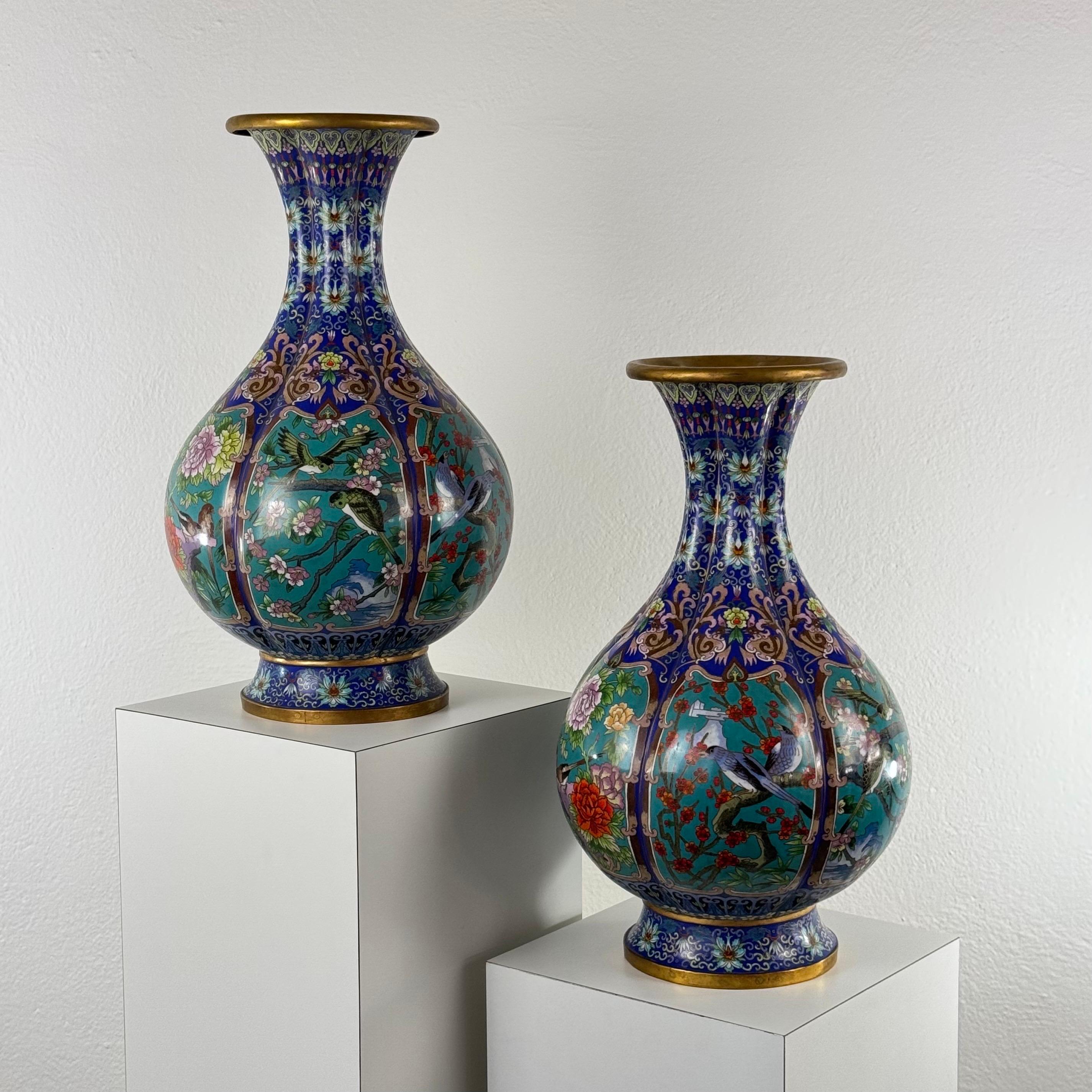 Une paire frappante et monumentale de vases en émail cloisonné, probablement d'origine chinoise, datant du début du 20e siècle (vers les années 1910). D'une hauteur de 51,5 cm et d'un diamètre généreux de 30 cm, chaque vase est une célébration de la
