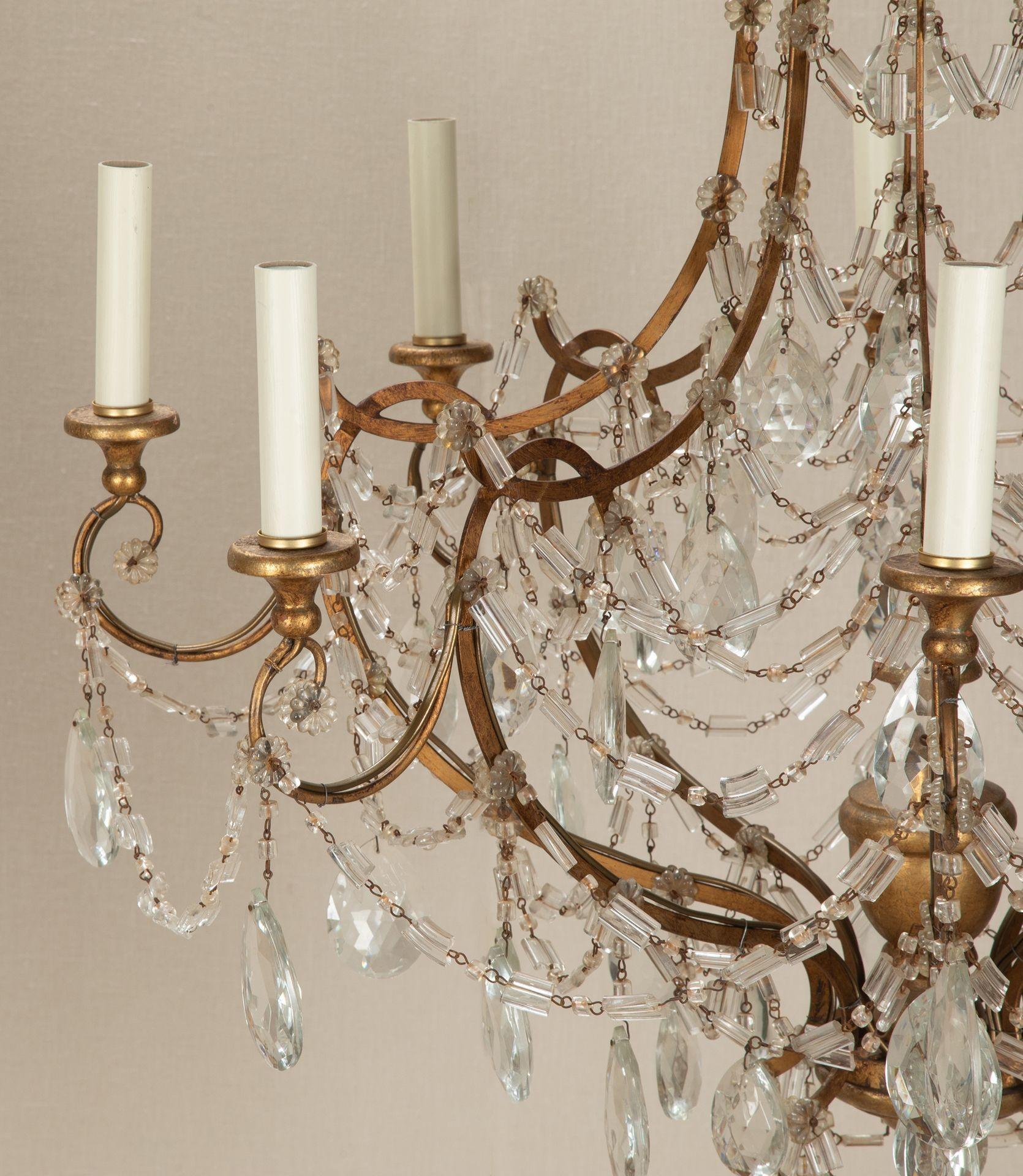 A wonderful pair of early 20th Century Italian gilt metal and gilt wood eight-light chandeliers, fully re-wired. The scrolling bell-form cage densely hung with tiers of rosette, pear and rope-chain cut crystal prisms, surrounding a central giltwood