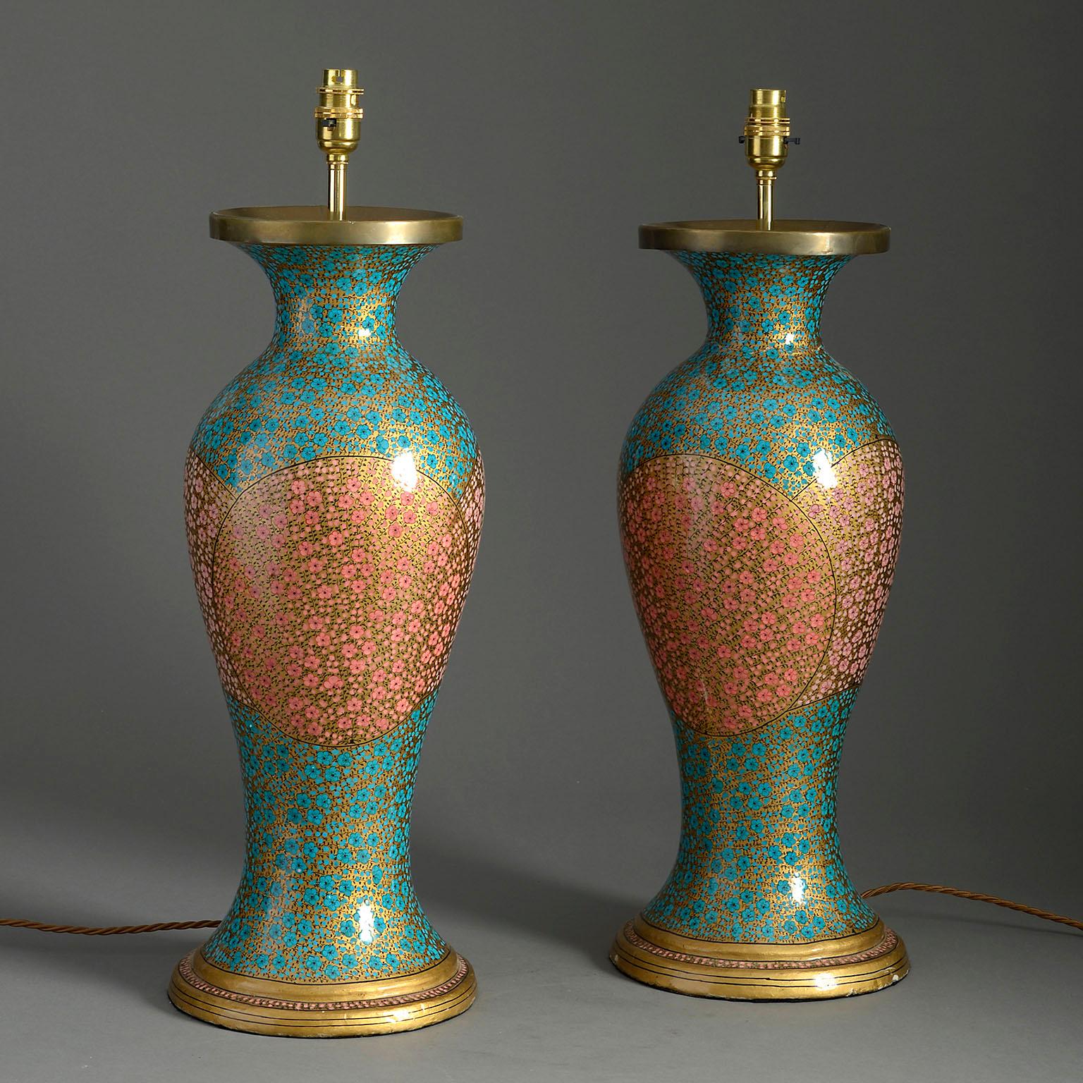 A pair of early 20th century Kashmiri lacquer table lamps of baluster form, decorated with gilded blossoms upon turquoise and pink grounds with gilded bases.

Wired to UK standards. These lamps can be re-wired to all international