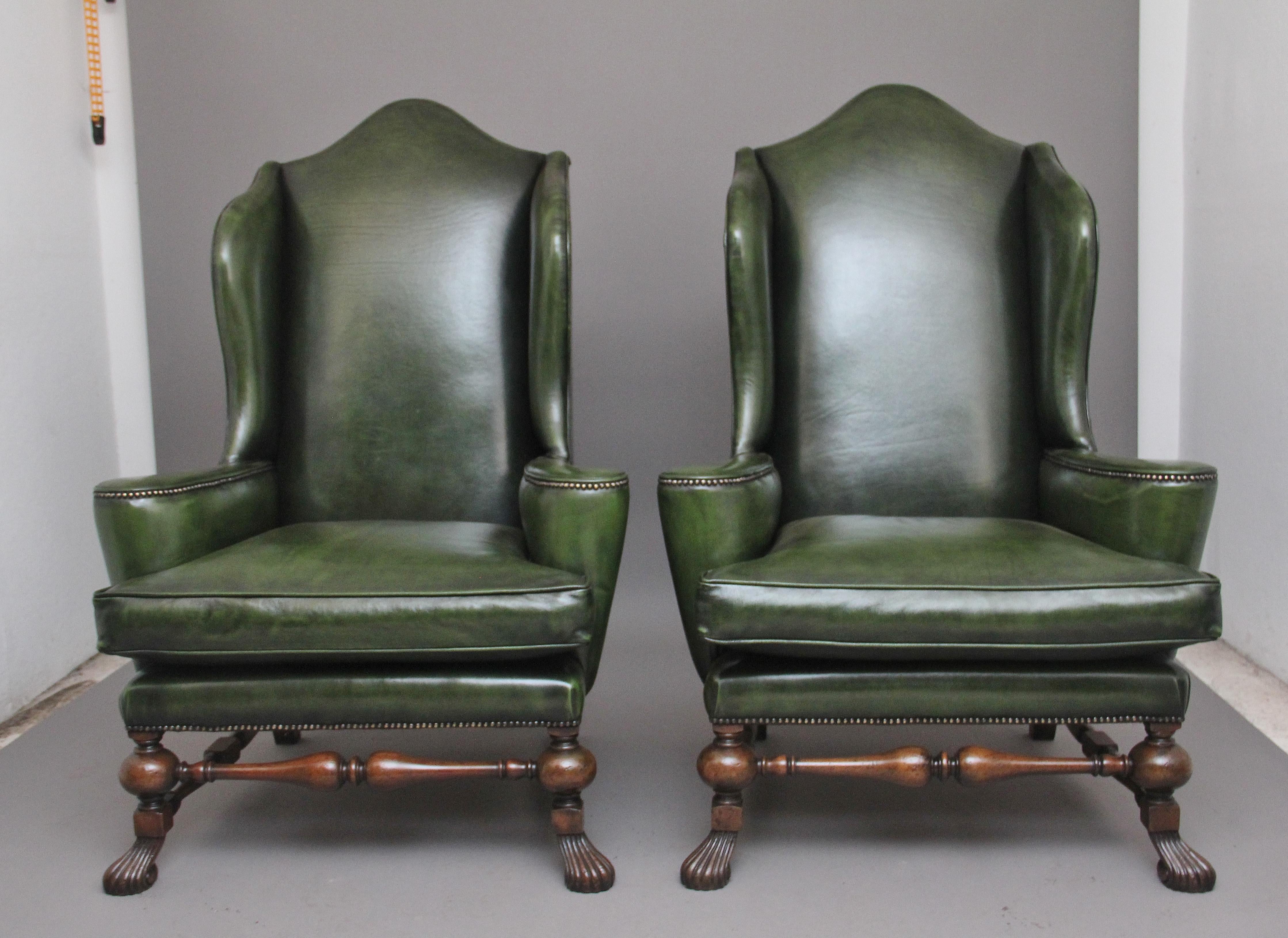 A fabulous pair of large early 19th Century walnut wingback armchairs in the Georgian style, just been reupholstered in a green leather with brass stud decoration, having a shaped high back with winged sides coming down to the curved arm supports,